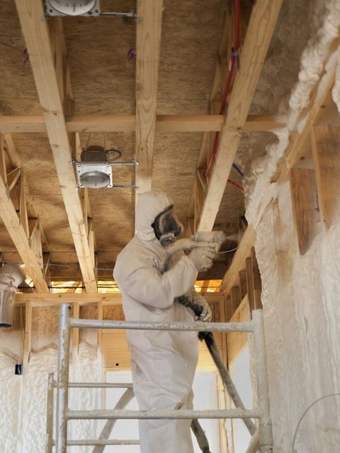 Spray Foam Insulation — Man in White Suit Spraying Foam Insulation in Seguin, TX