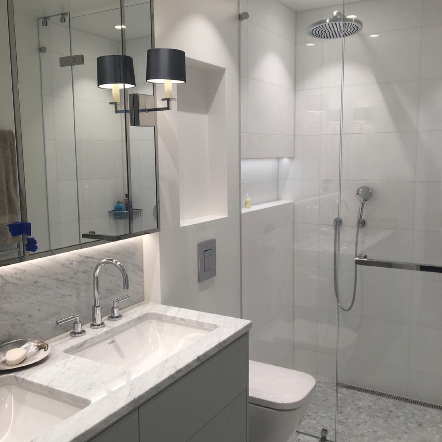 Klassisk-moderne hvitt bad med marmorvask, glassdusj og takbelysning.