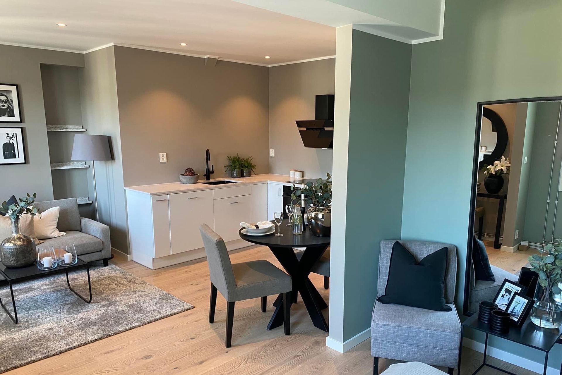 Moderne kjøkken med lysegrå skap, hvit benkeplate og tregulv.