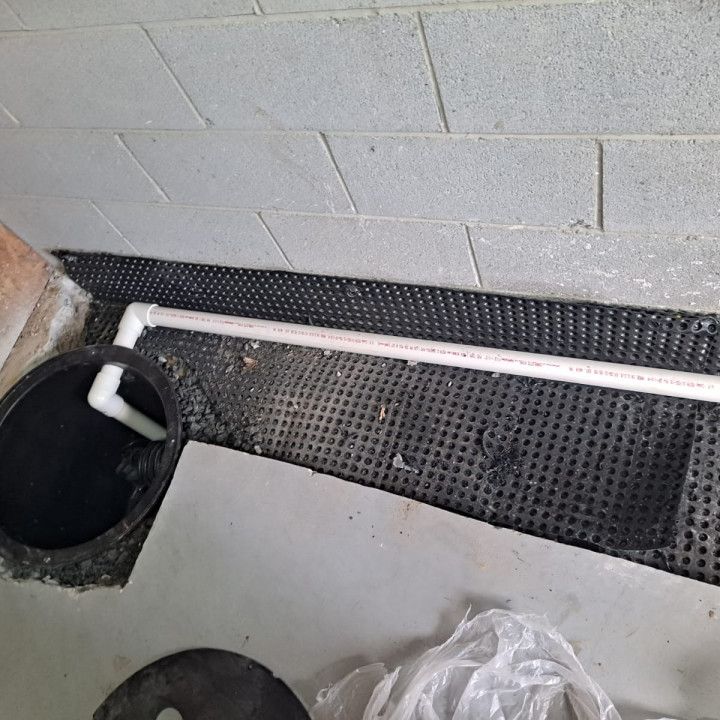 Woman in straw hat smiles, holding wine glass near a lake.