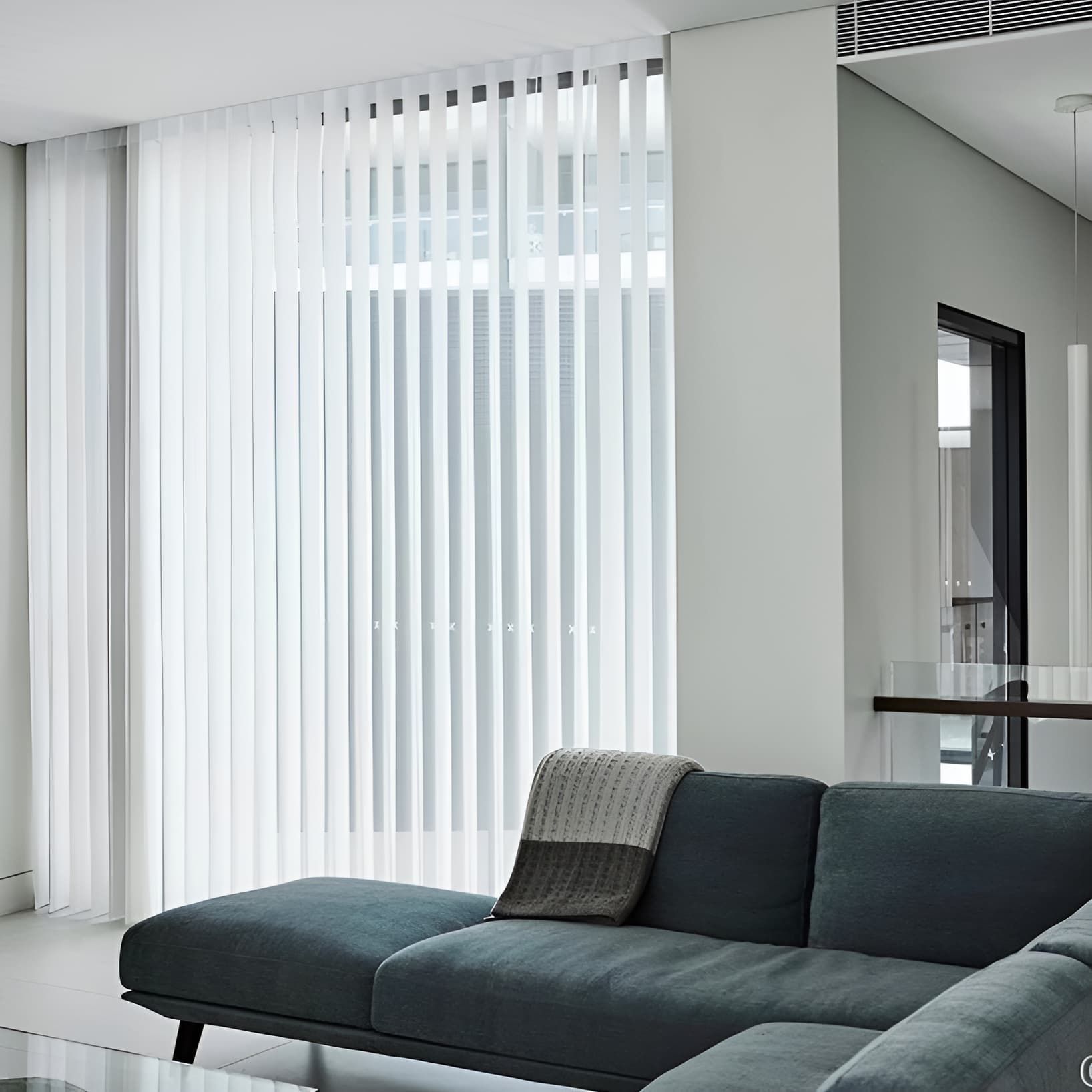 A Living Room With A Blue Couch And White Vertical Blinds — Caba's Drapery In Coffs Harbour, NSW