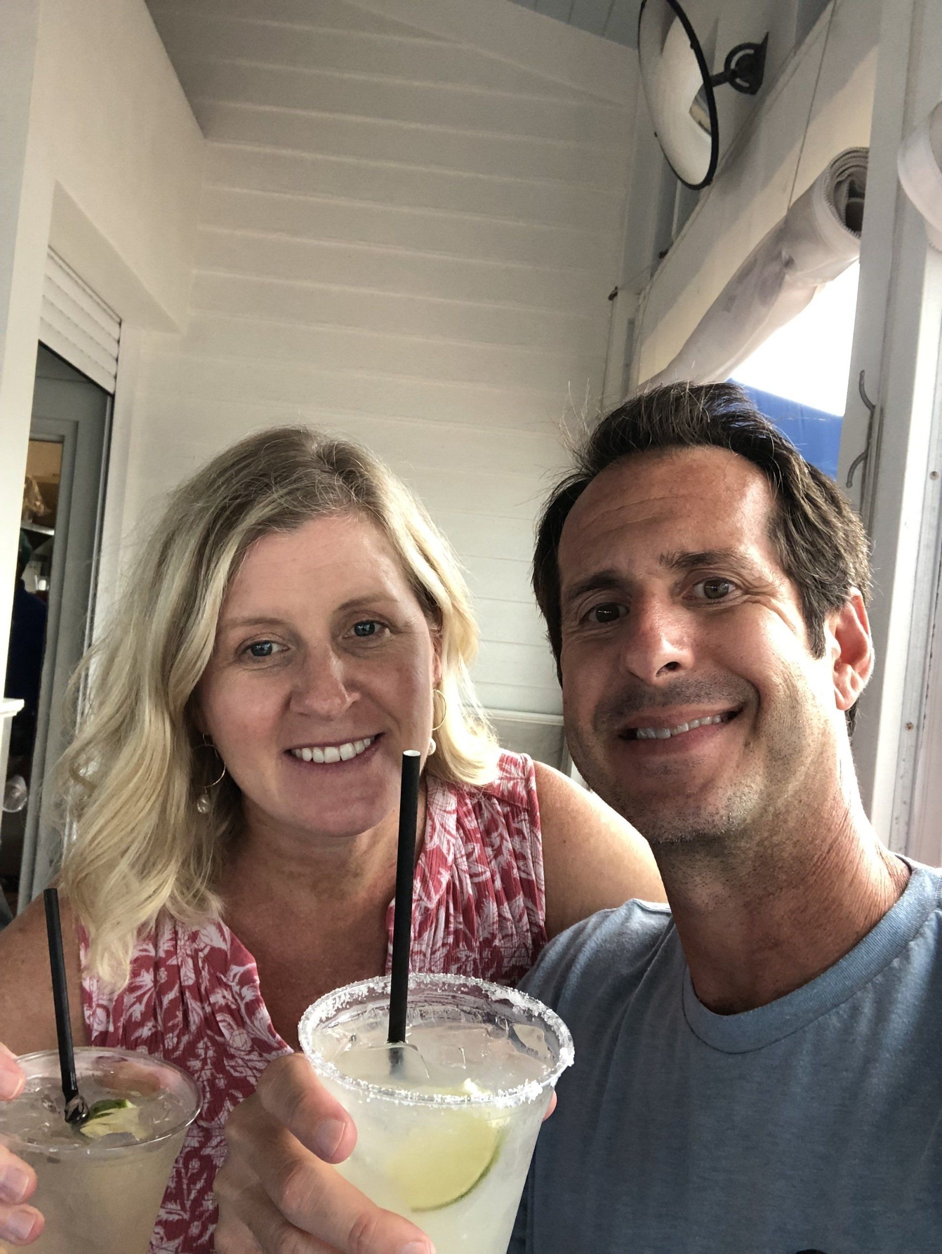A man and a woman are holding drinks with straws and smiling for the camera.