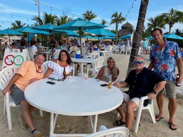 A group of people are sitting at a table on the beach.