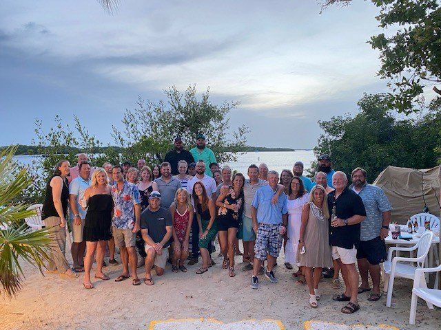A large group of people are posing for a picture on a beach.