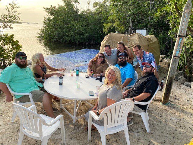 A group of people are sitting around a table on the beach.