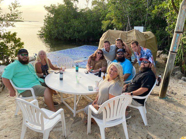 A group of people are sitting around a table on the beach.