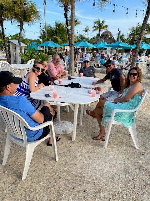 A group of people are sitting around a table on the beach