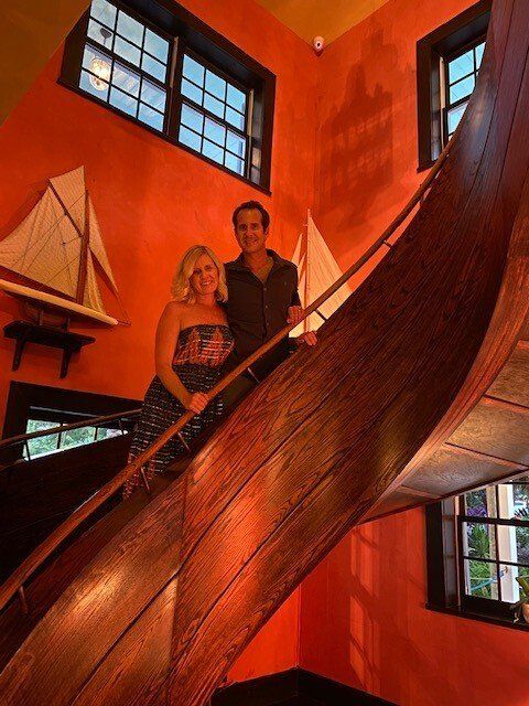 A man and a woman are standing on a wooden staircase.