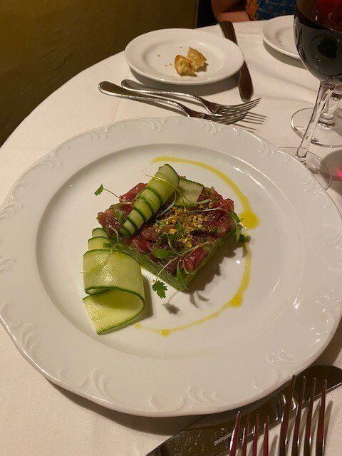 A plate of food on a table next to a glass of wine