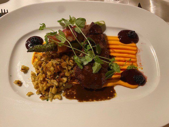 A white plate topped with meat and vegetables on a table.