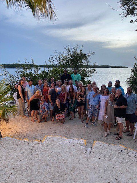 A large group of people are posing for a picture on a beach.