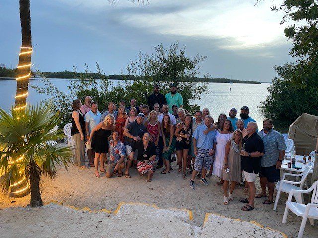 A large group of people are posing for a picture on a beach.