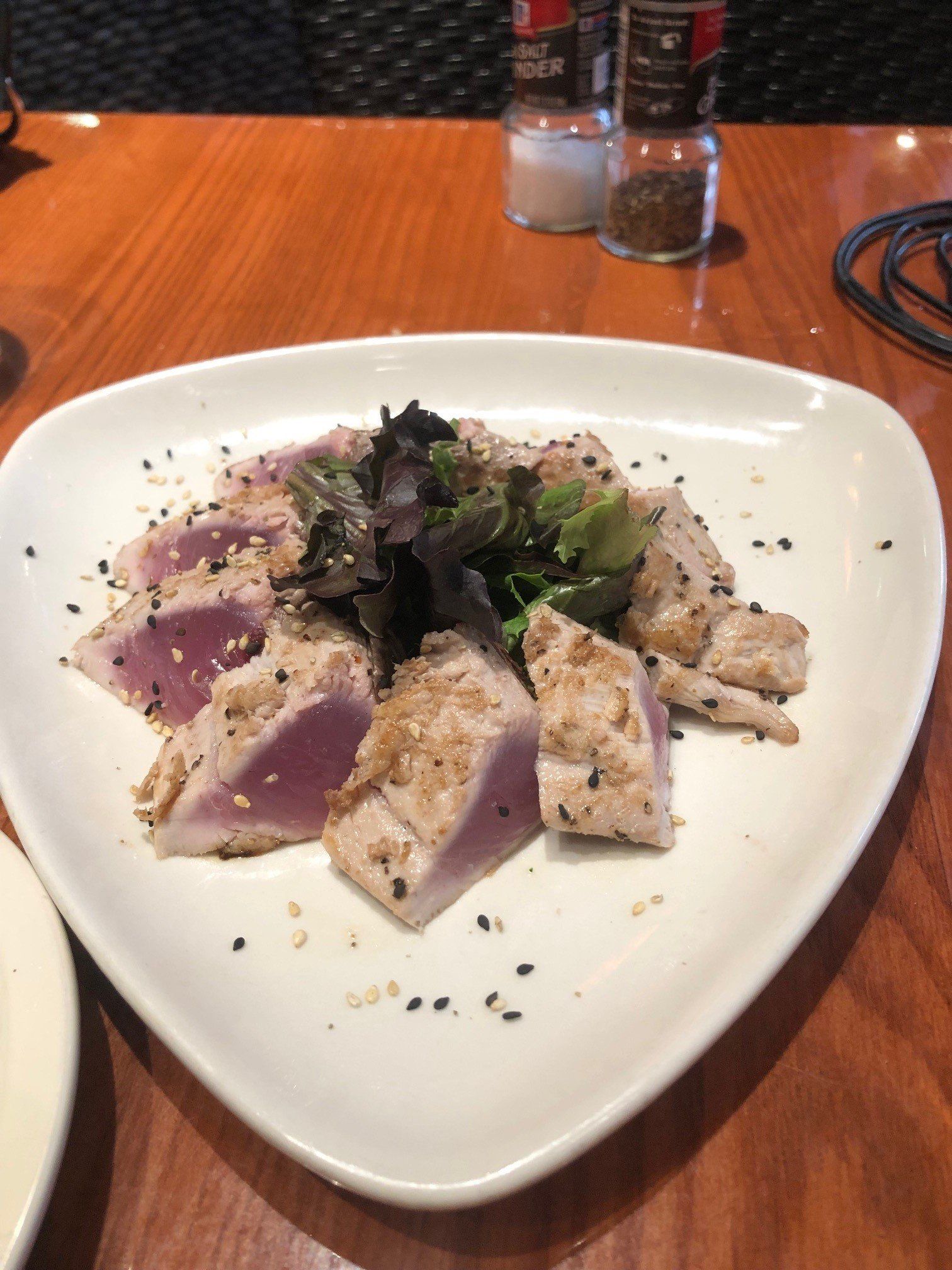 A white plate topped with meat and vegetables on a wooden table.