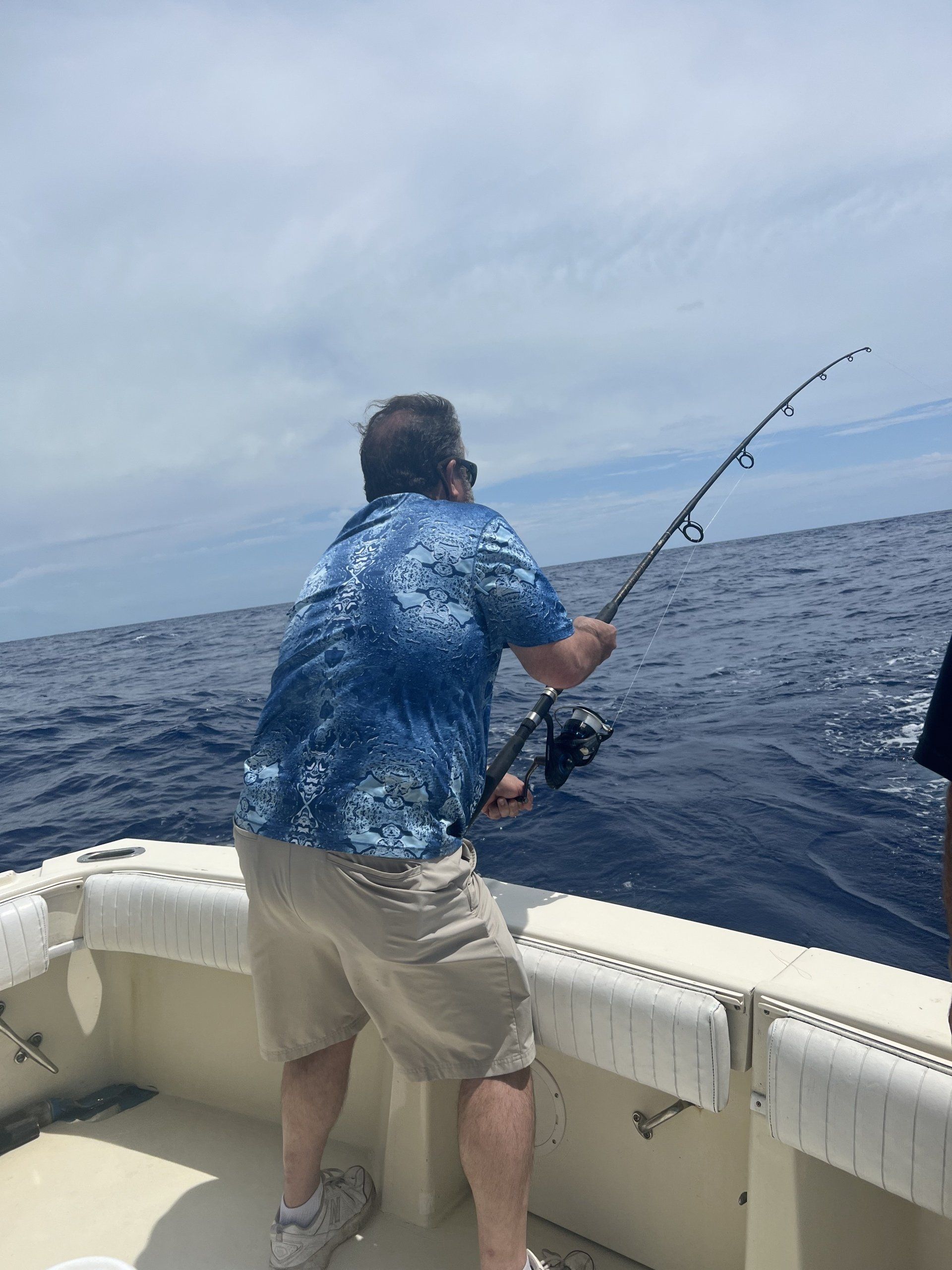 A man is fishing on a boat in the ocean.