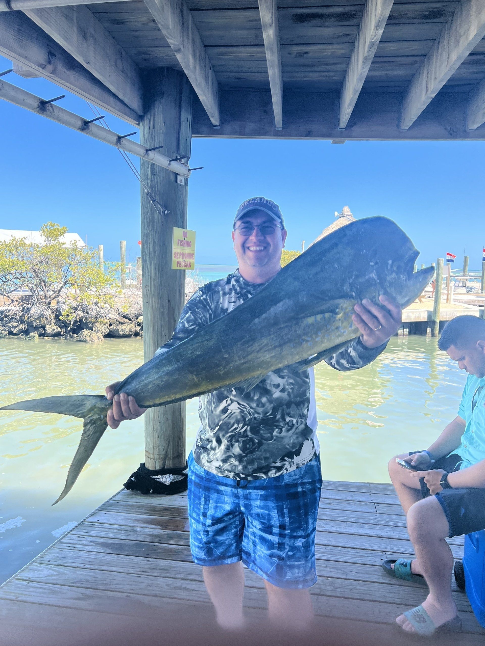 A man is holding a large fish on a dock.