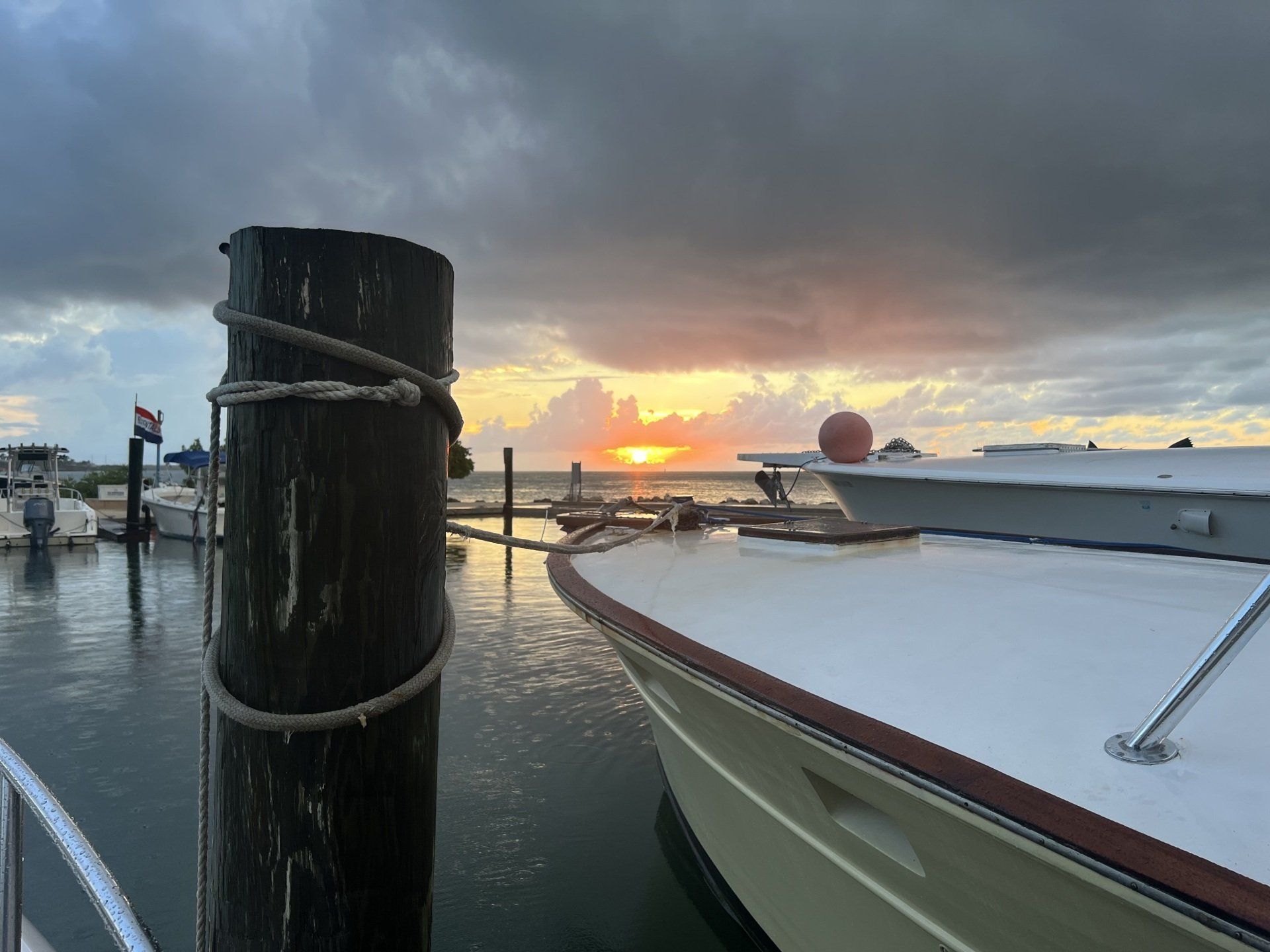 A boat is docked at a dock with a sunset in the background.