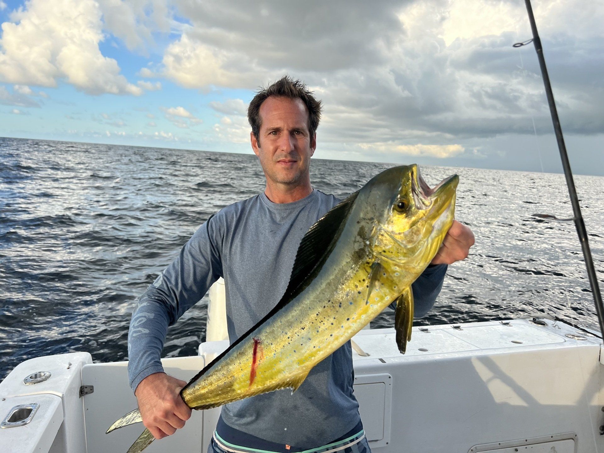 A man is holding a large fish on a boat in the ocean.