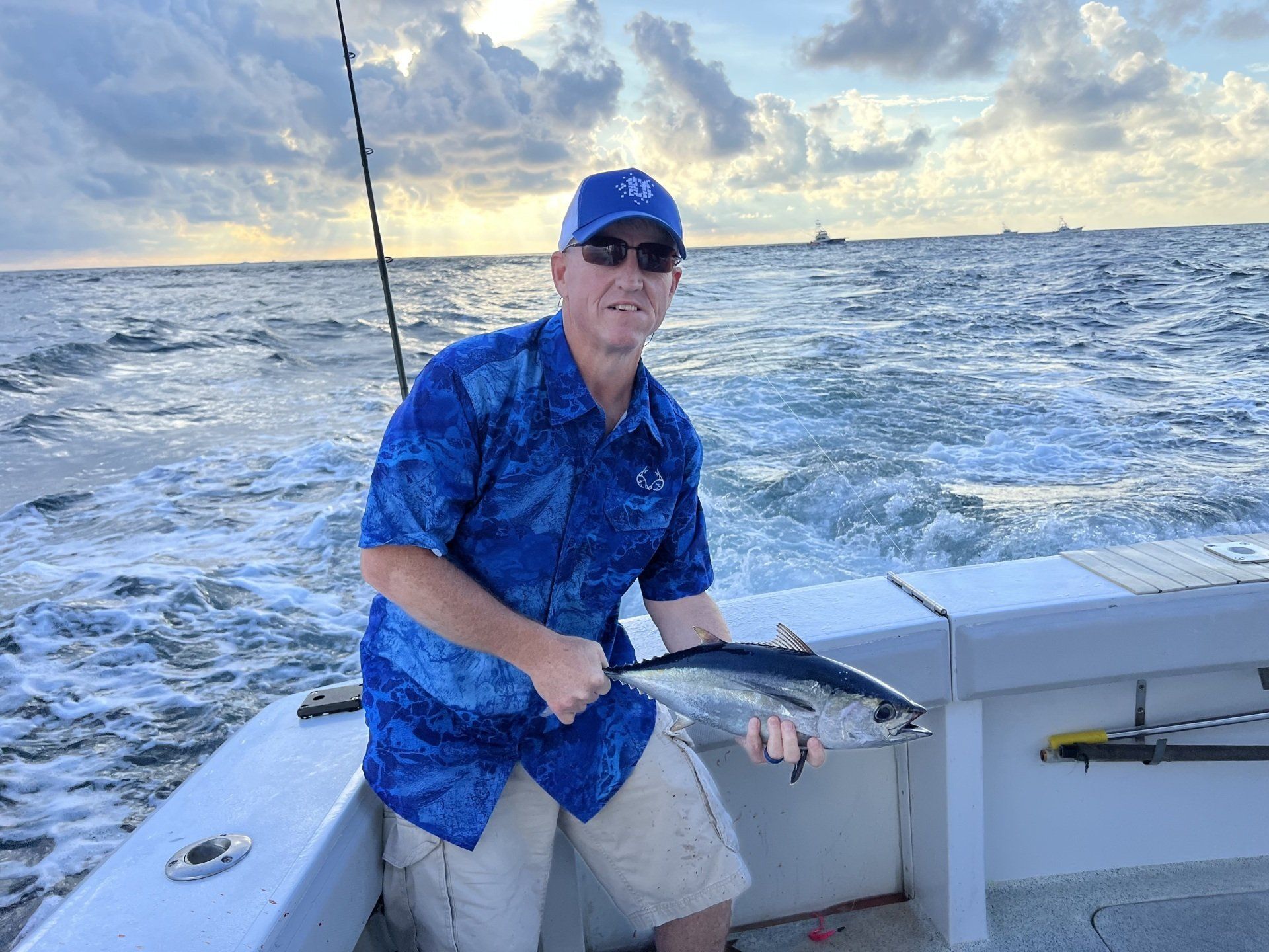 A man is sitting on a boat holding a fish.