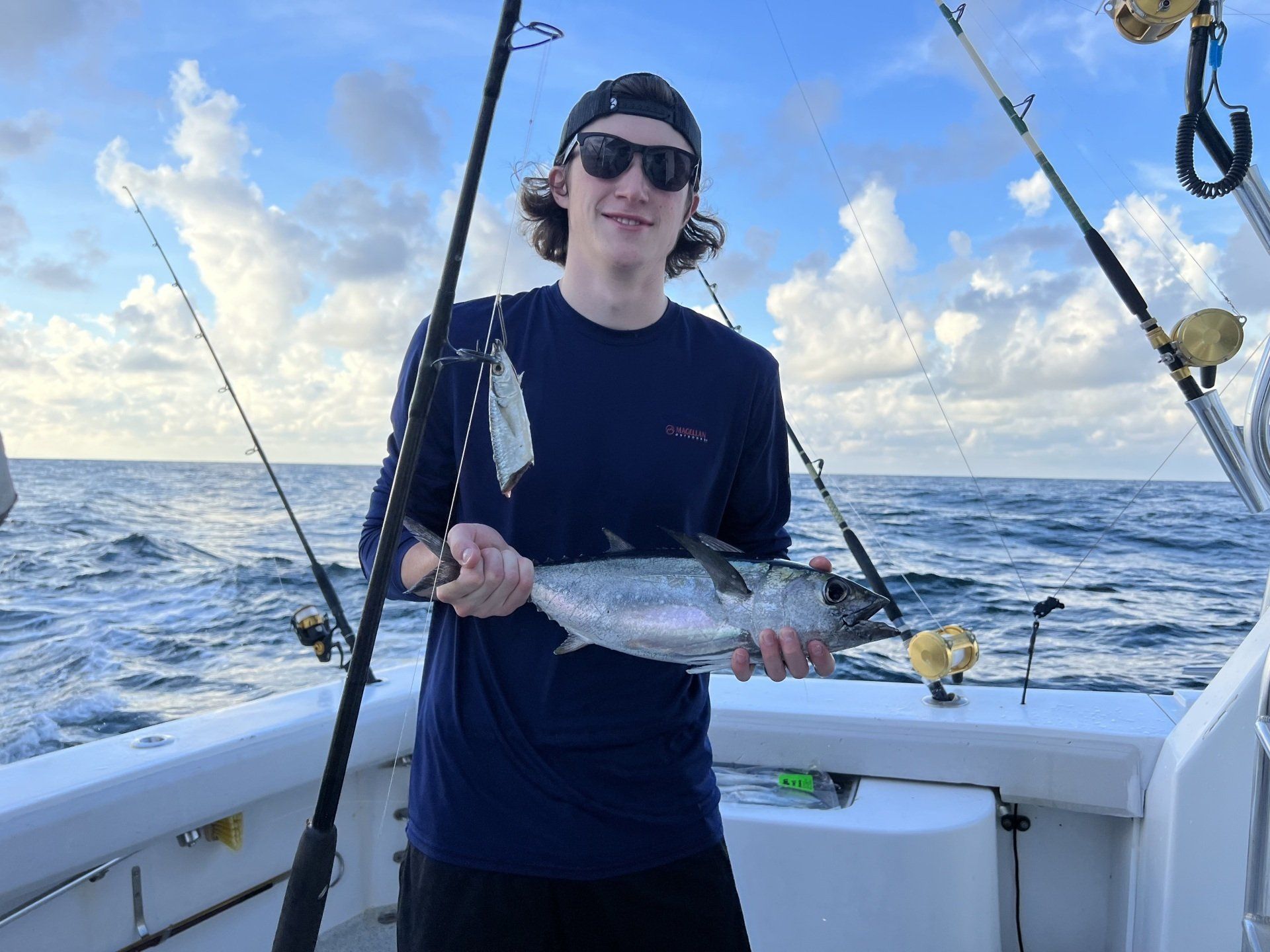 A man is holding a fish on a boat in the ocean.