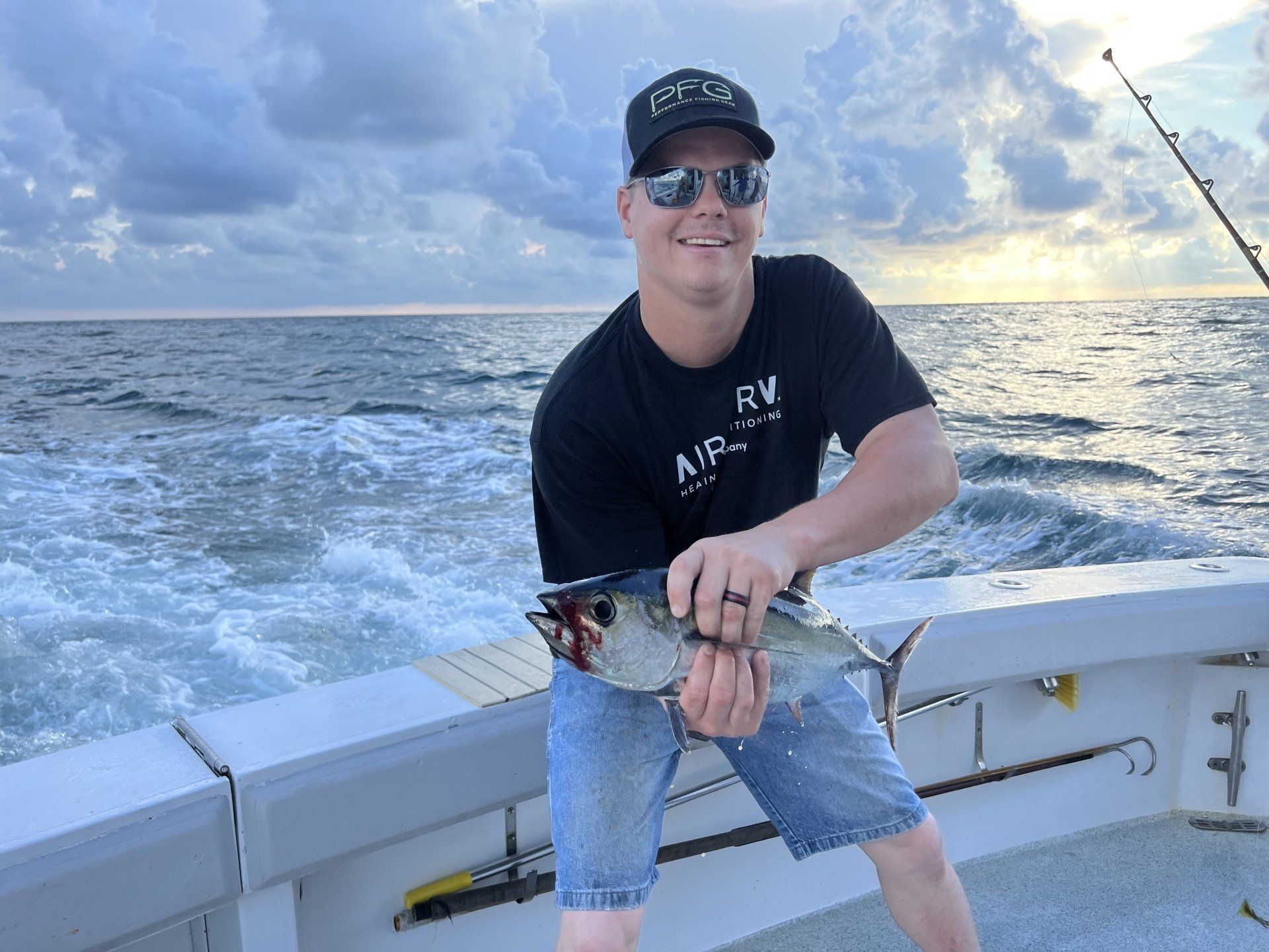A man is holding a fish on a boat in the ocean.