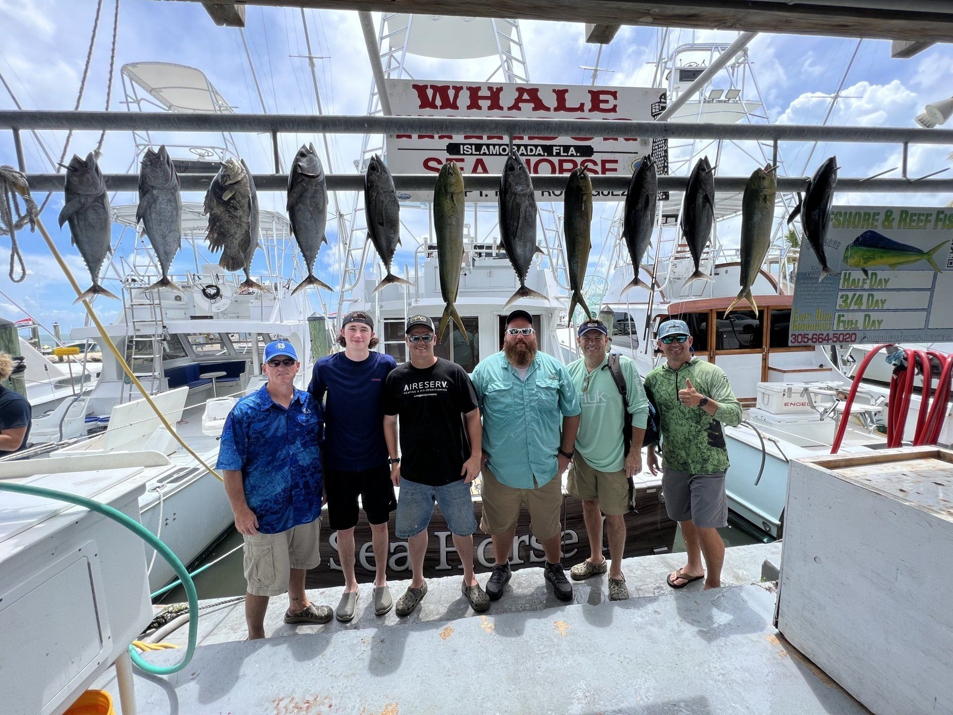 A group of men are posing for a picture on the deck of a fishing boat.