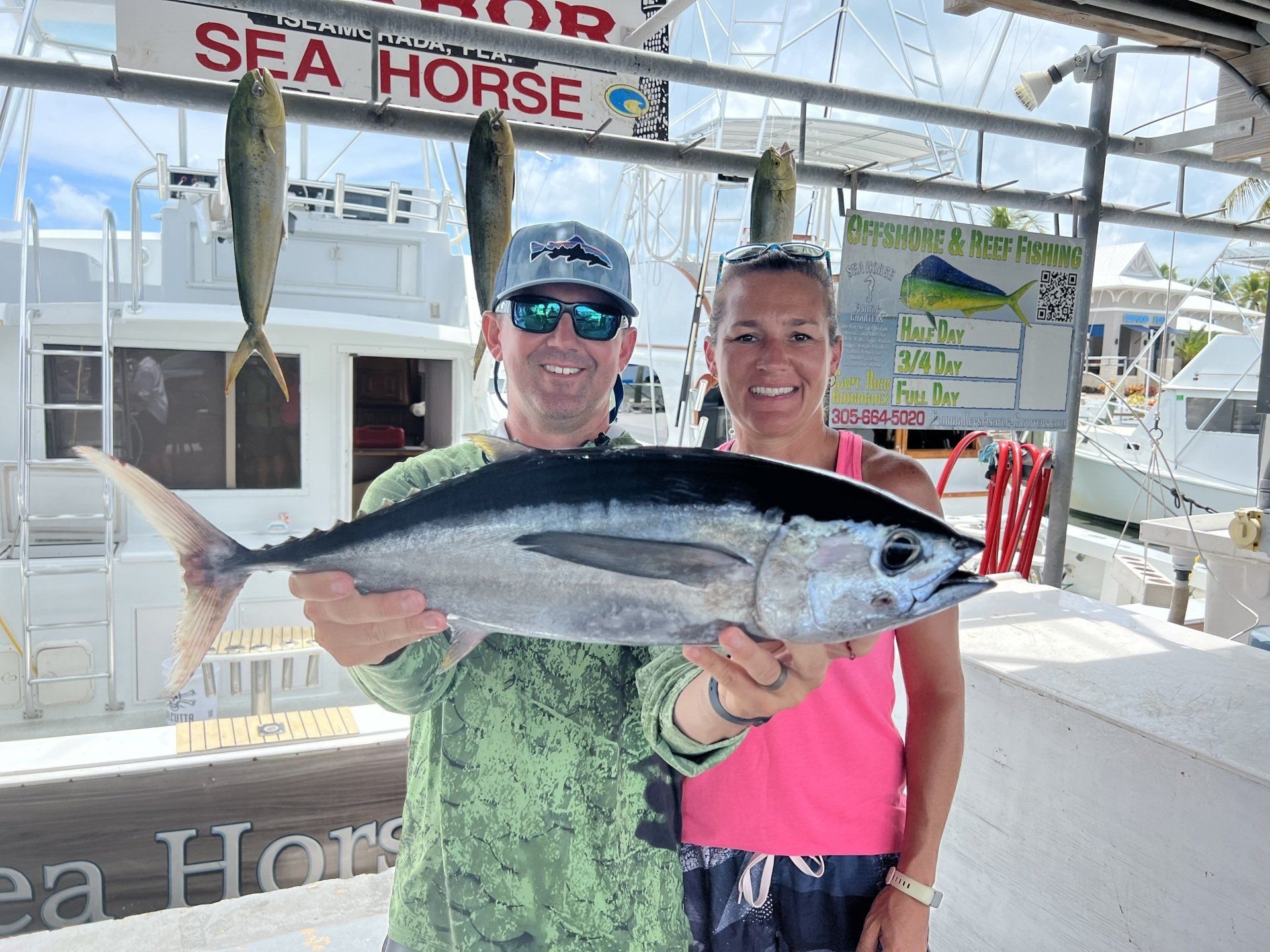 A man and a woman are holding a large fish on a boat.