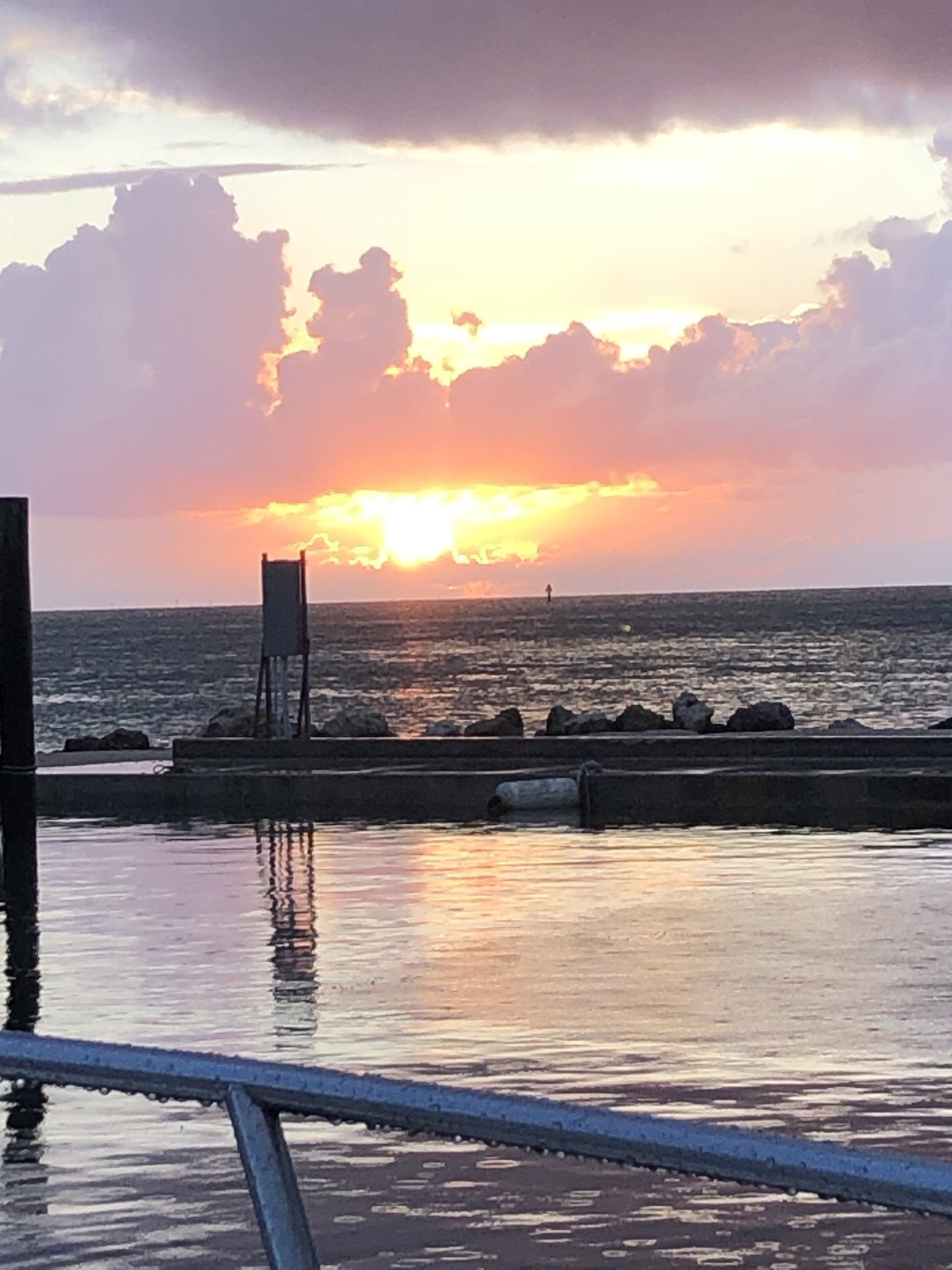 A sunset over a body of water with a dock in the foreground.