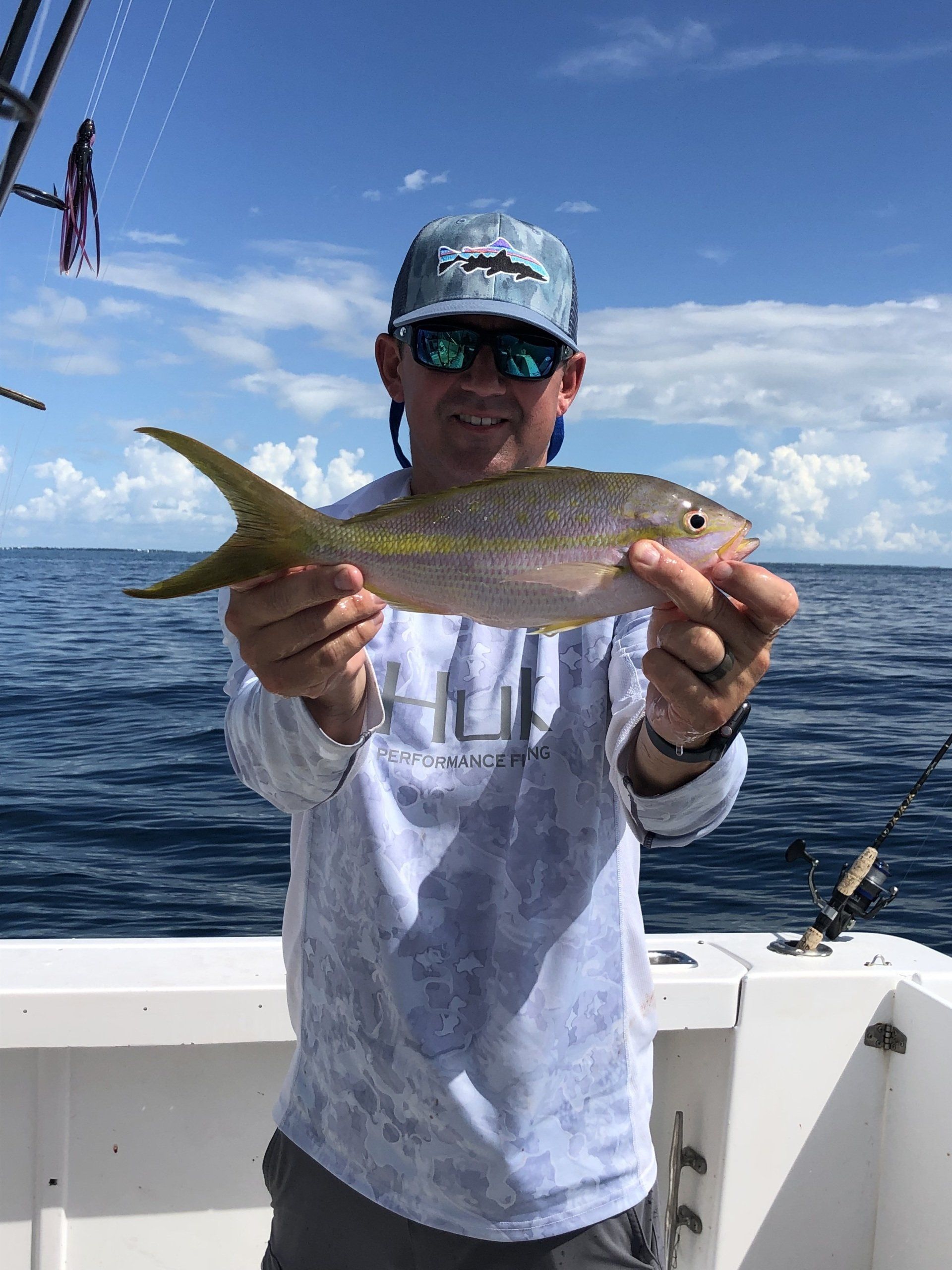 A man is holding a fish on a boat in the ocean.