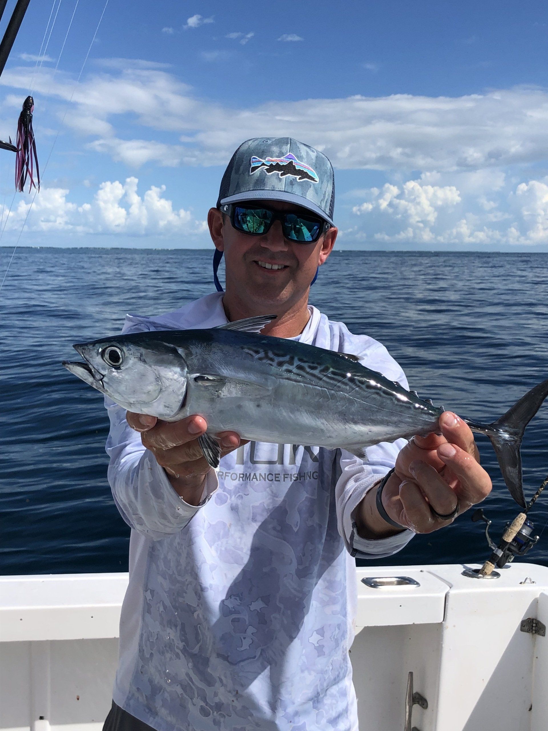 A man is holding a fish on a boat in the ocean.