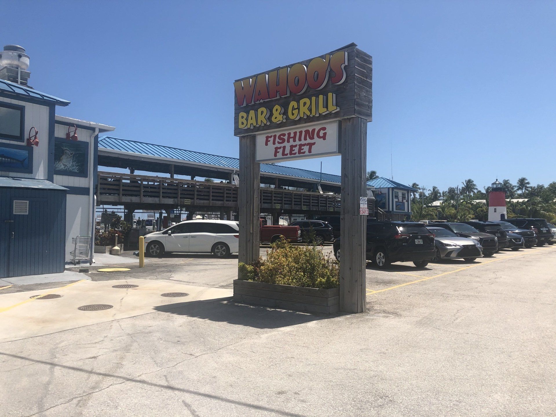 A row of cars are parked in front of a bar and grill.