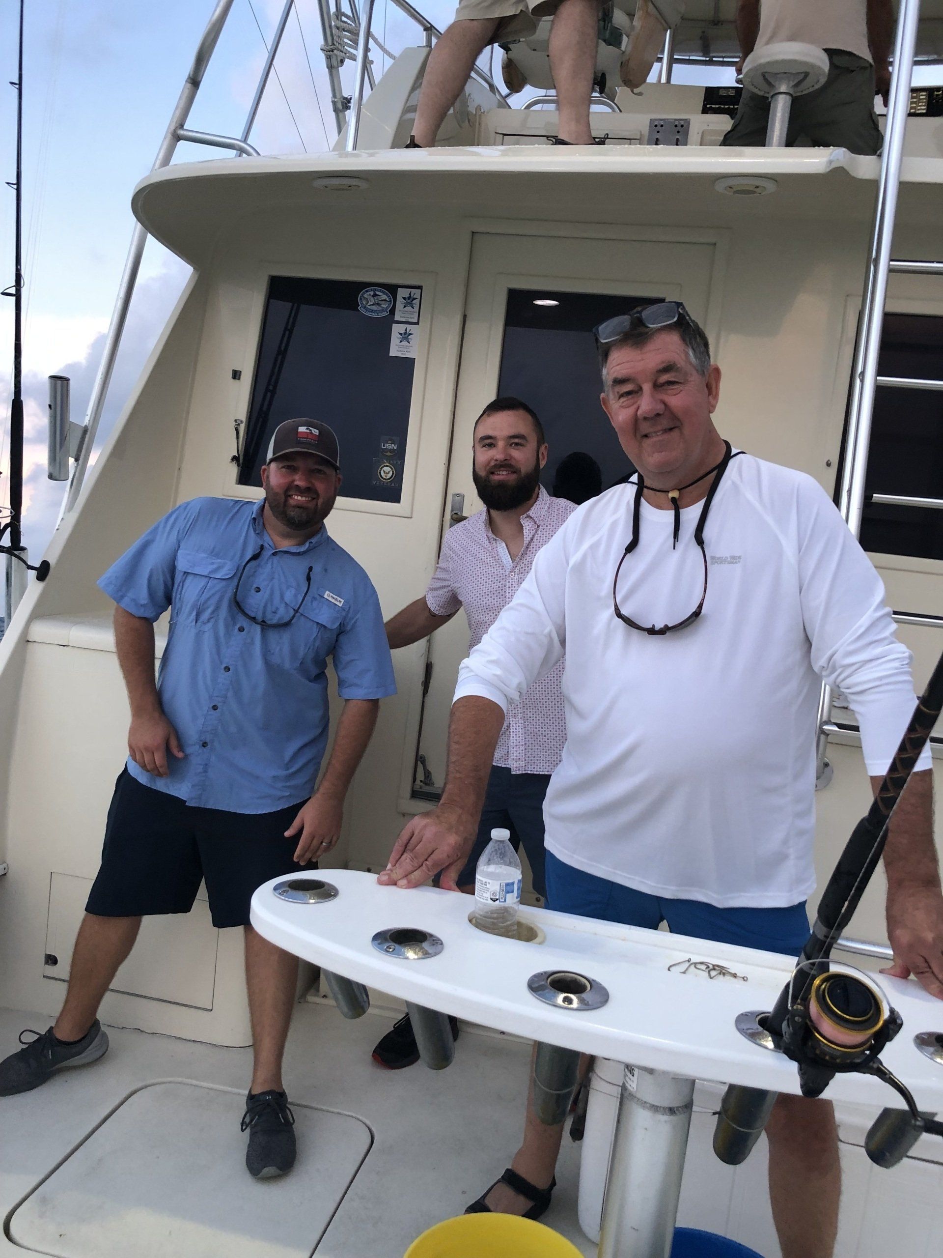 Three men are standing on the deck of a boat