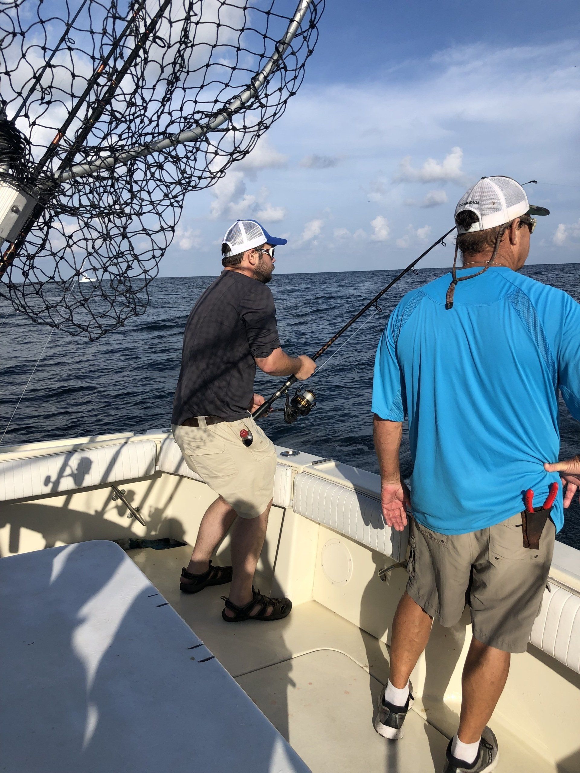 Two men are fishing on a boat in the ocean.