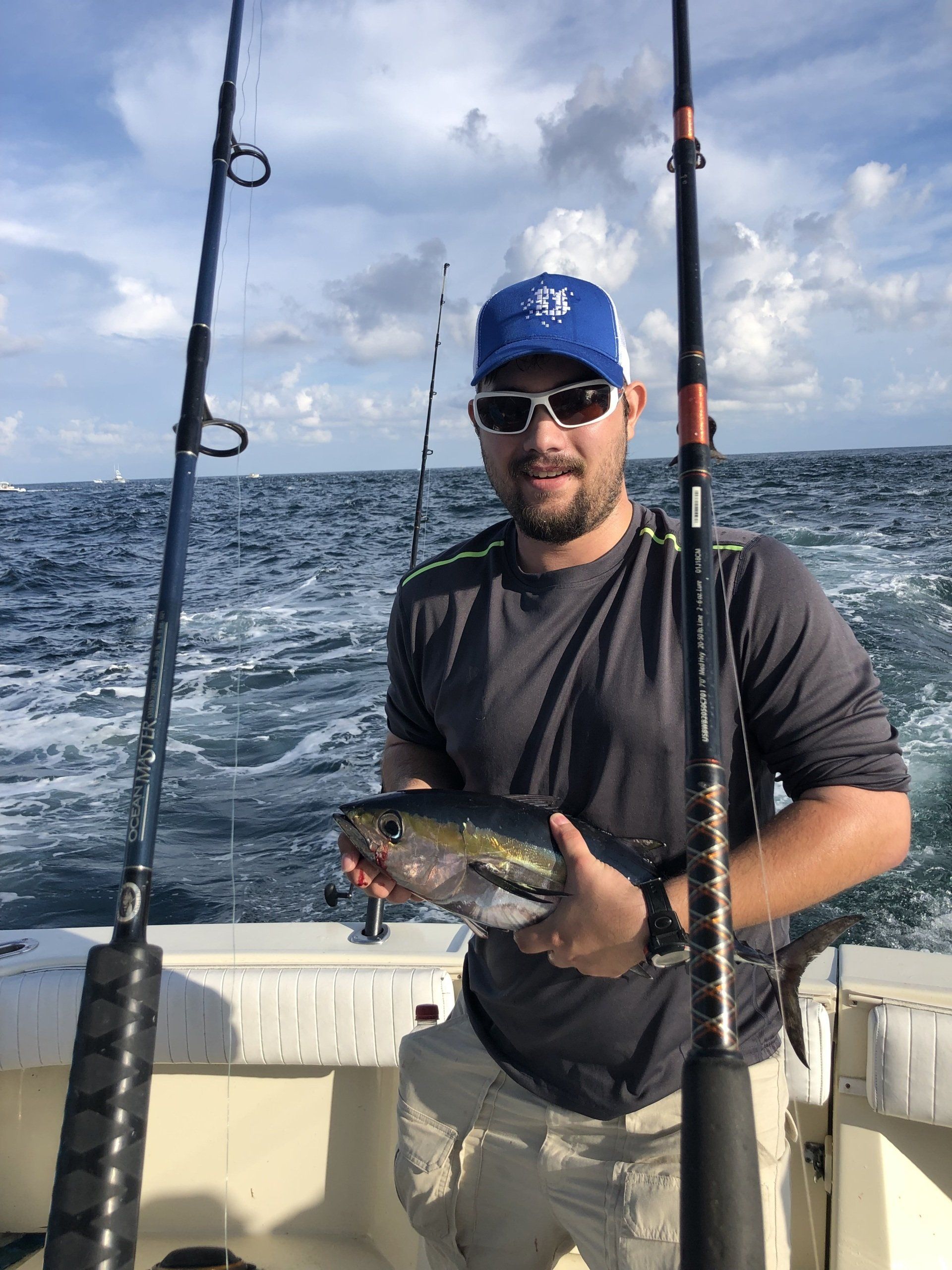 A man is holding a fish on a boat in the ocean.