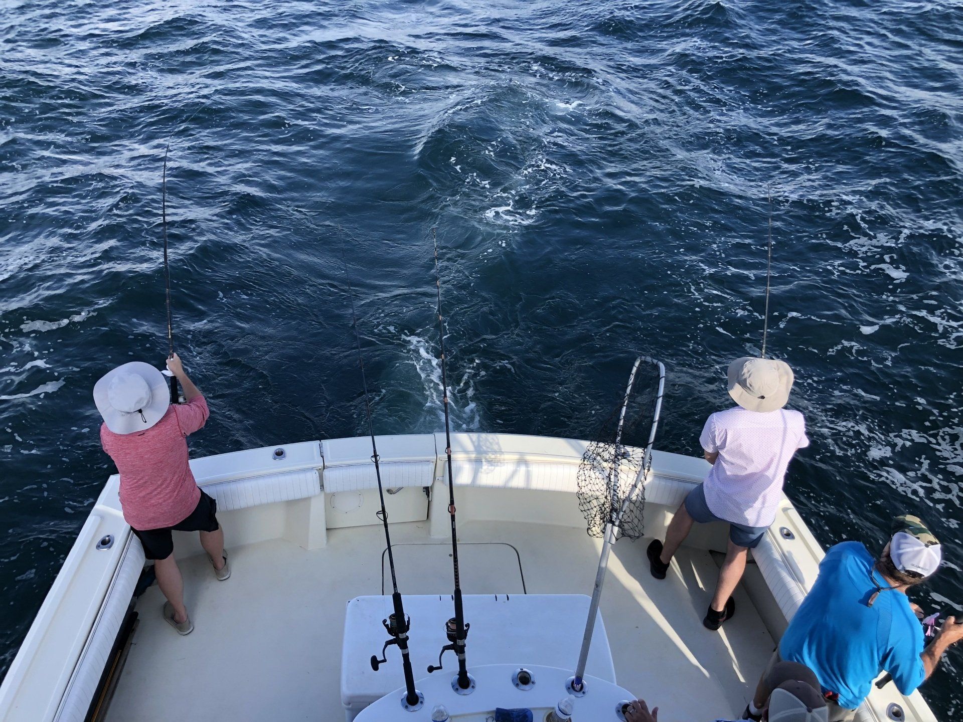 A group of people are fishing on a boat in the ocean.