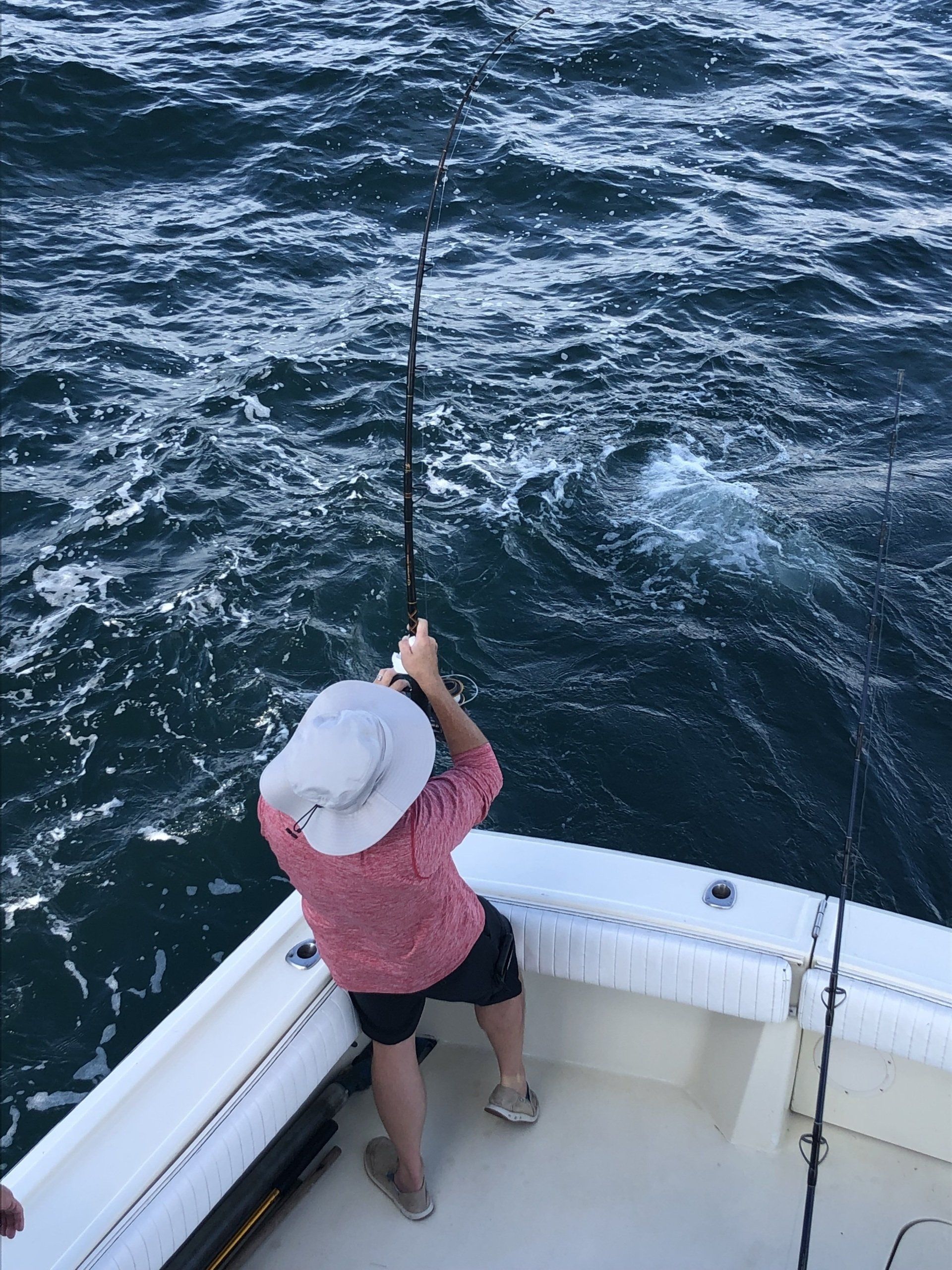 A woman is fishing on a boat in the ocean