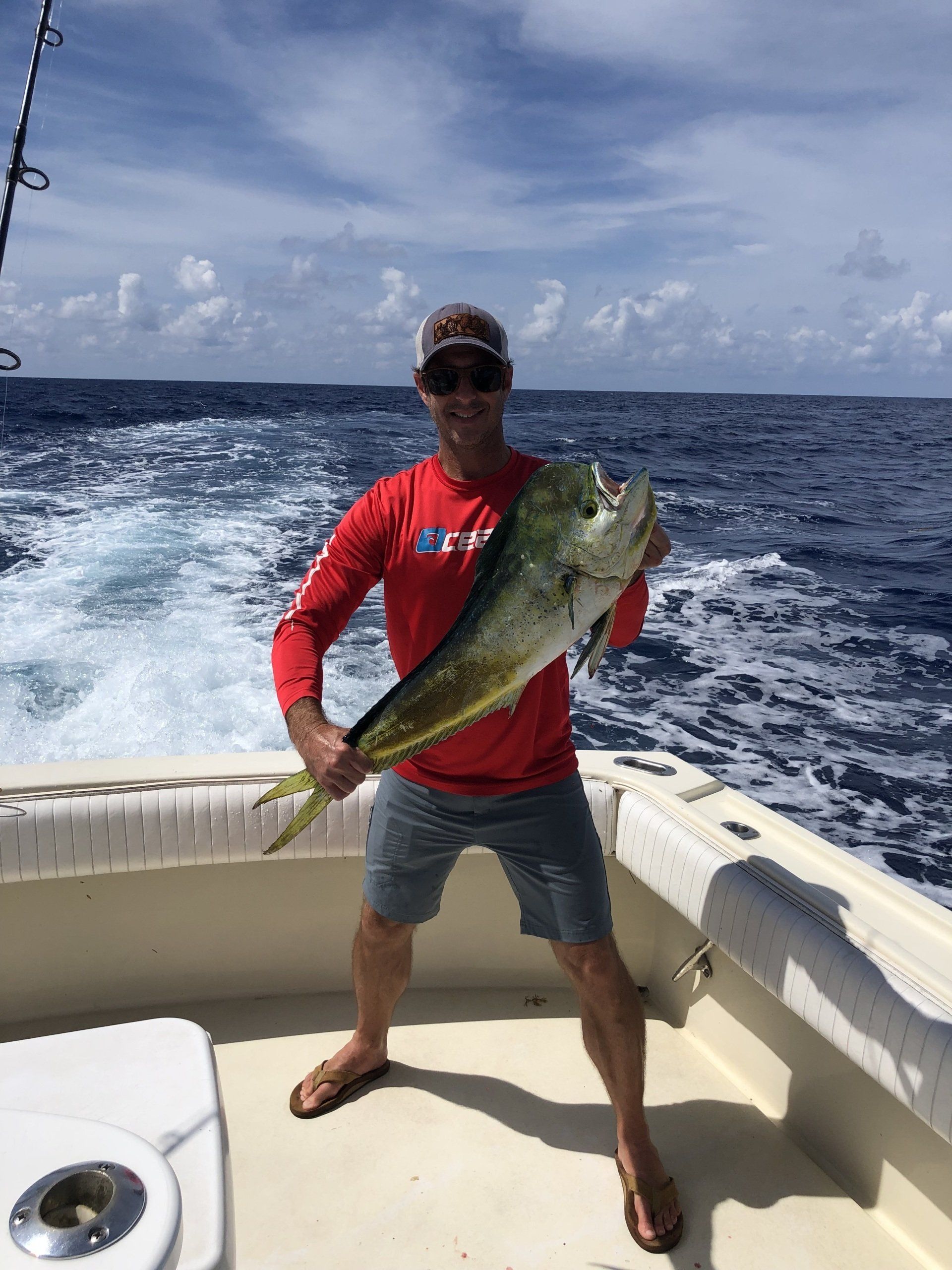 A man is holding a large fish on a boat in the ocean.