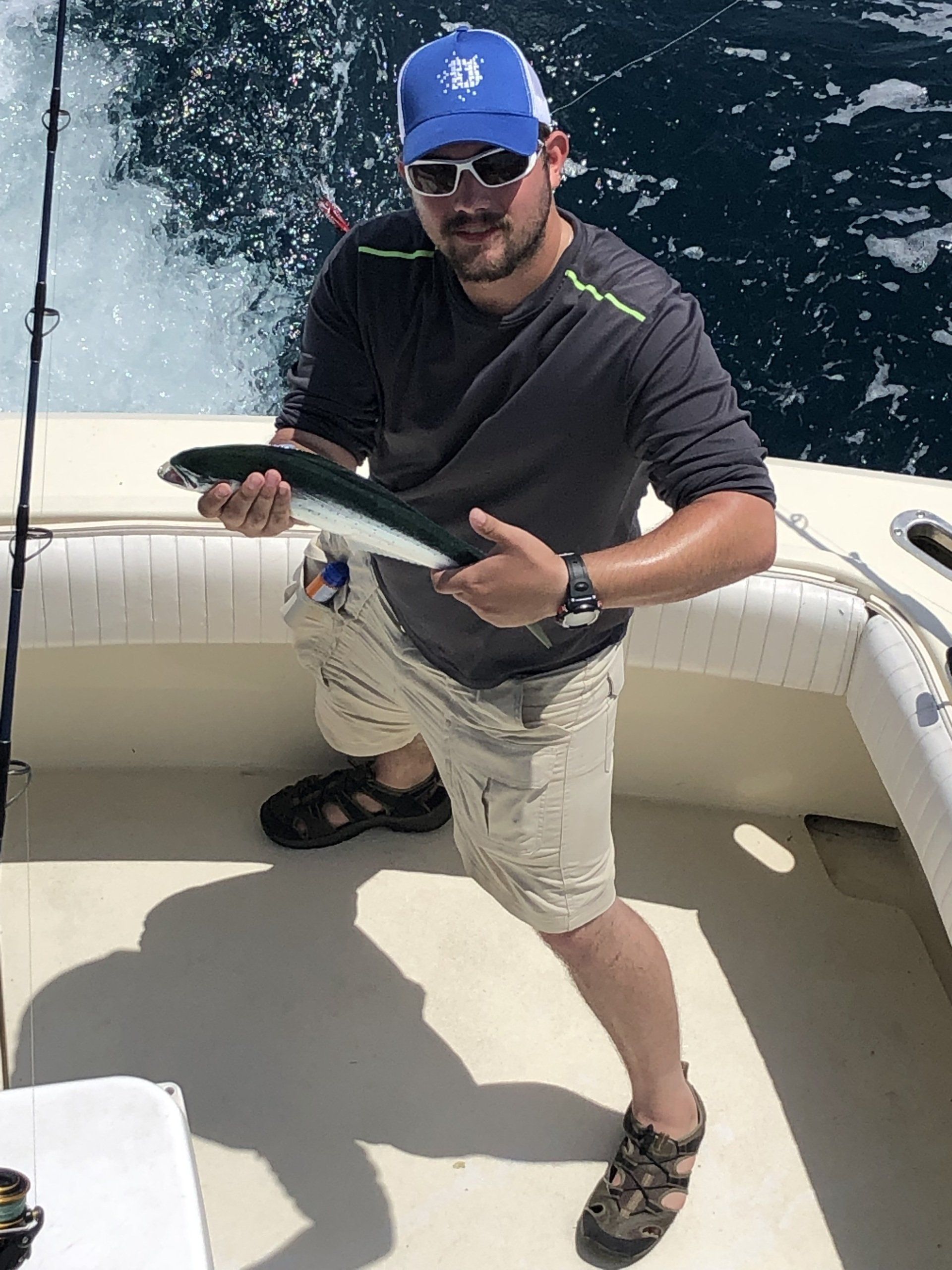 A man is standing on a boat holding a fish.