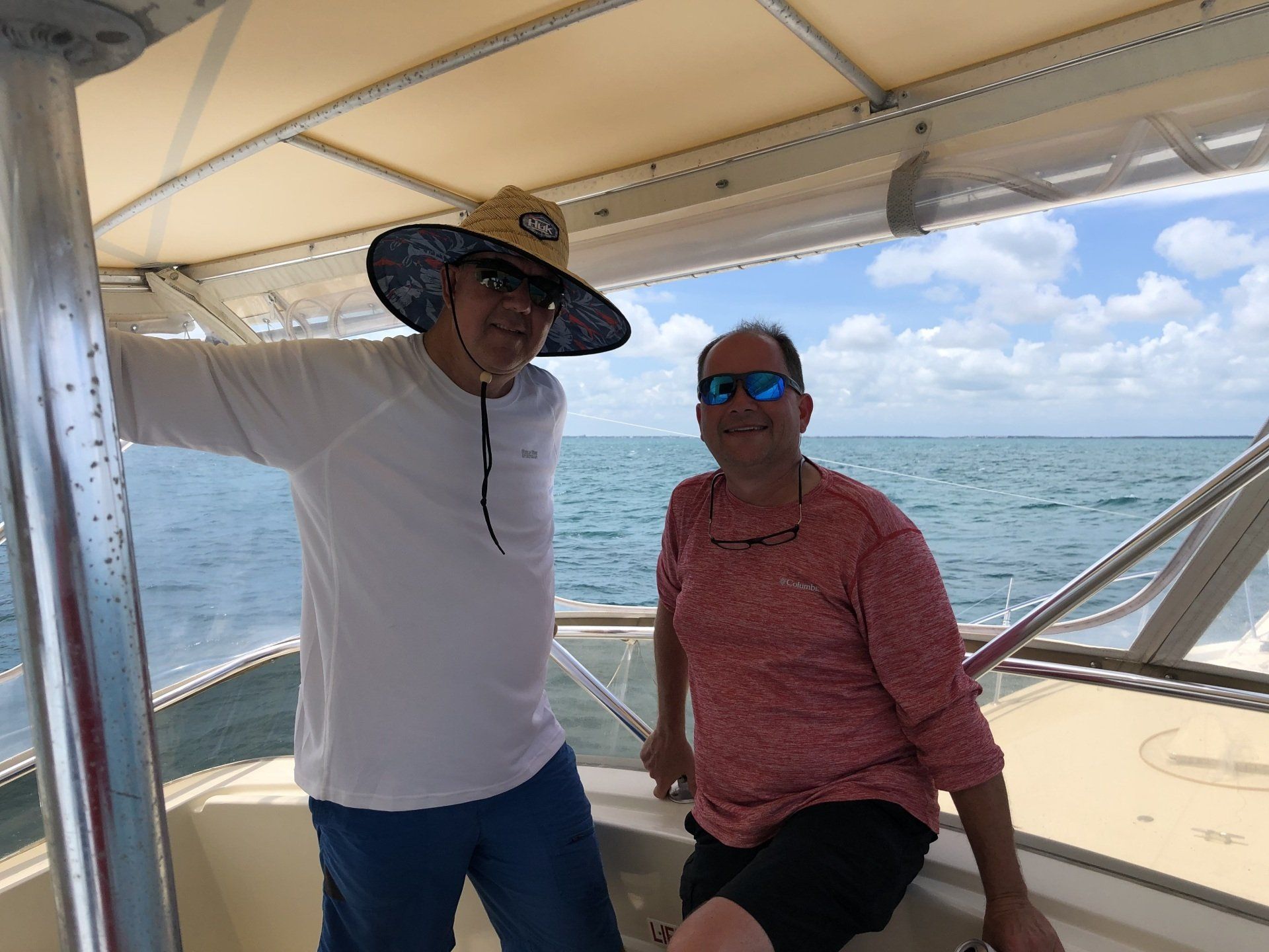 Two men are posing for a picture on a boat in the ocean.