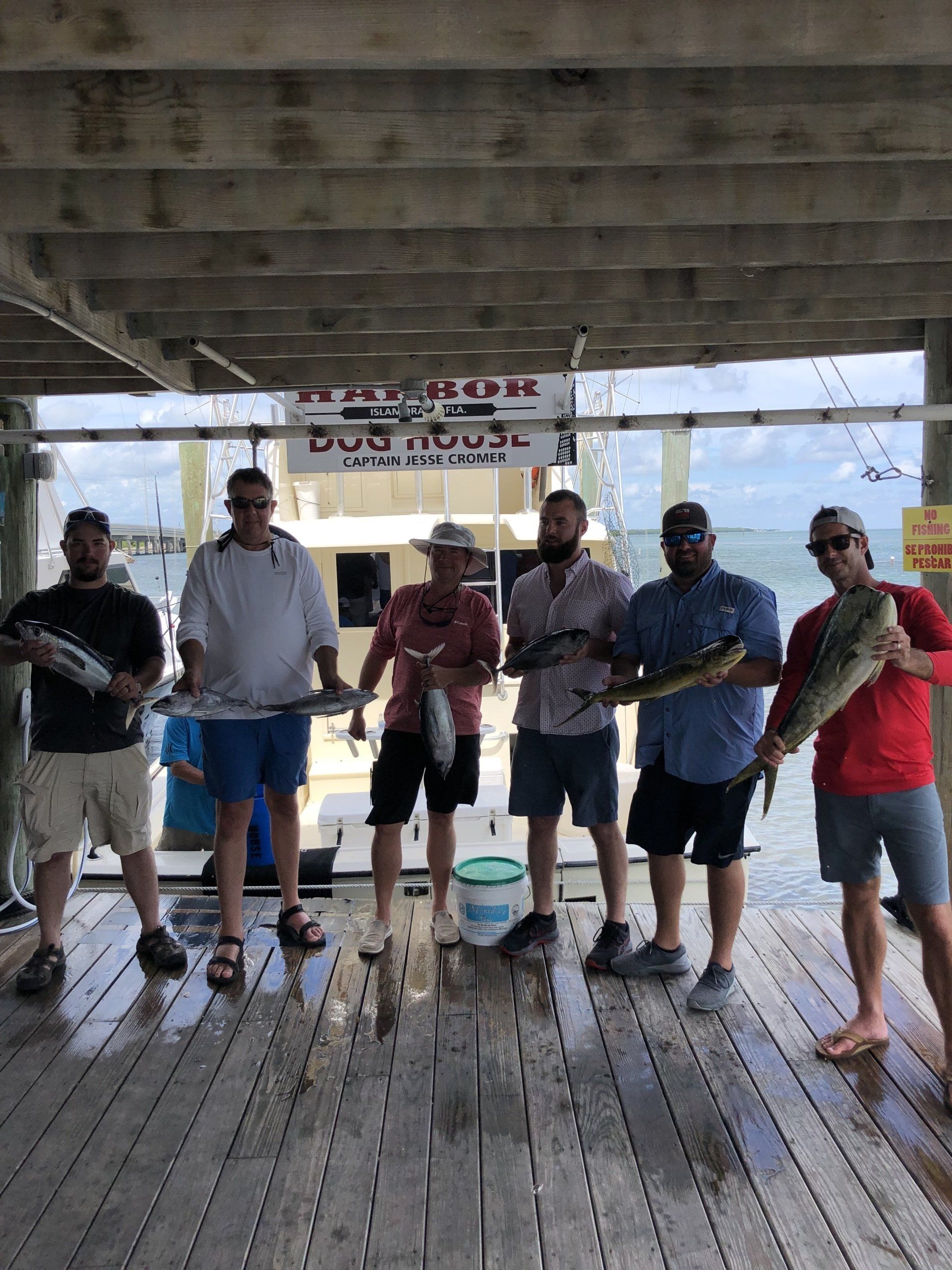 A group of men are standing on a dock holding fish.
