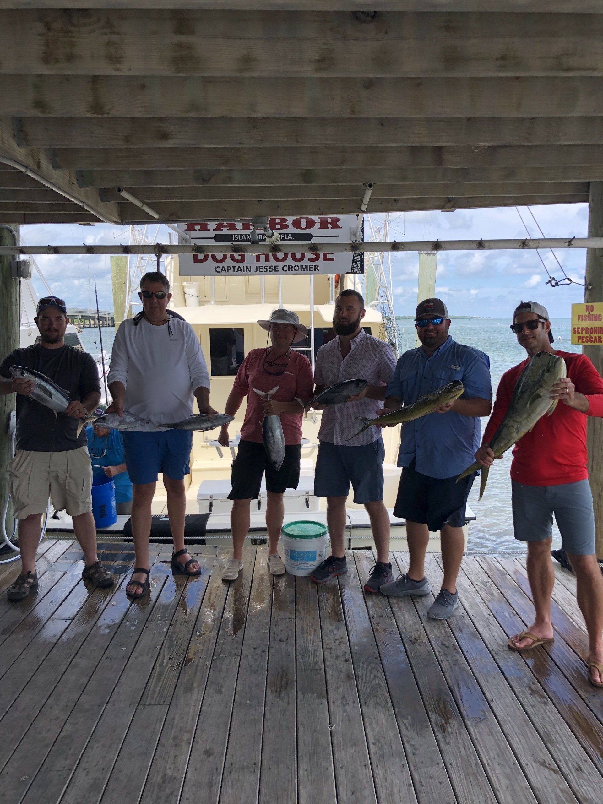 A group of men are standing on a dock holding fish.