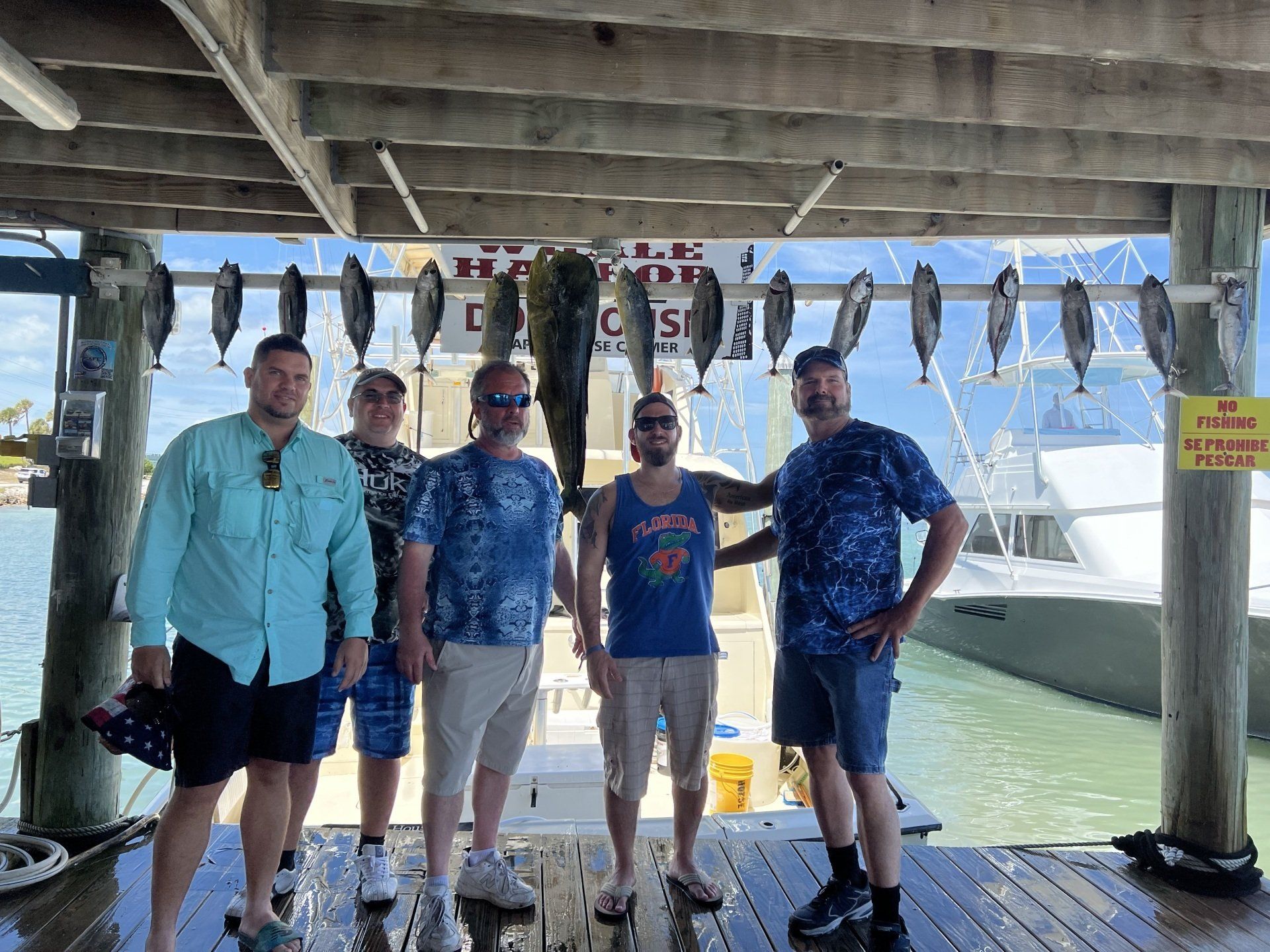 A group of men are standing on a dock holding fish.