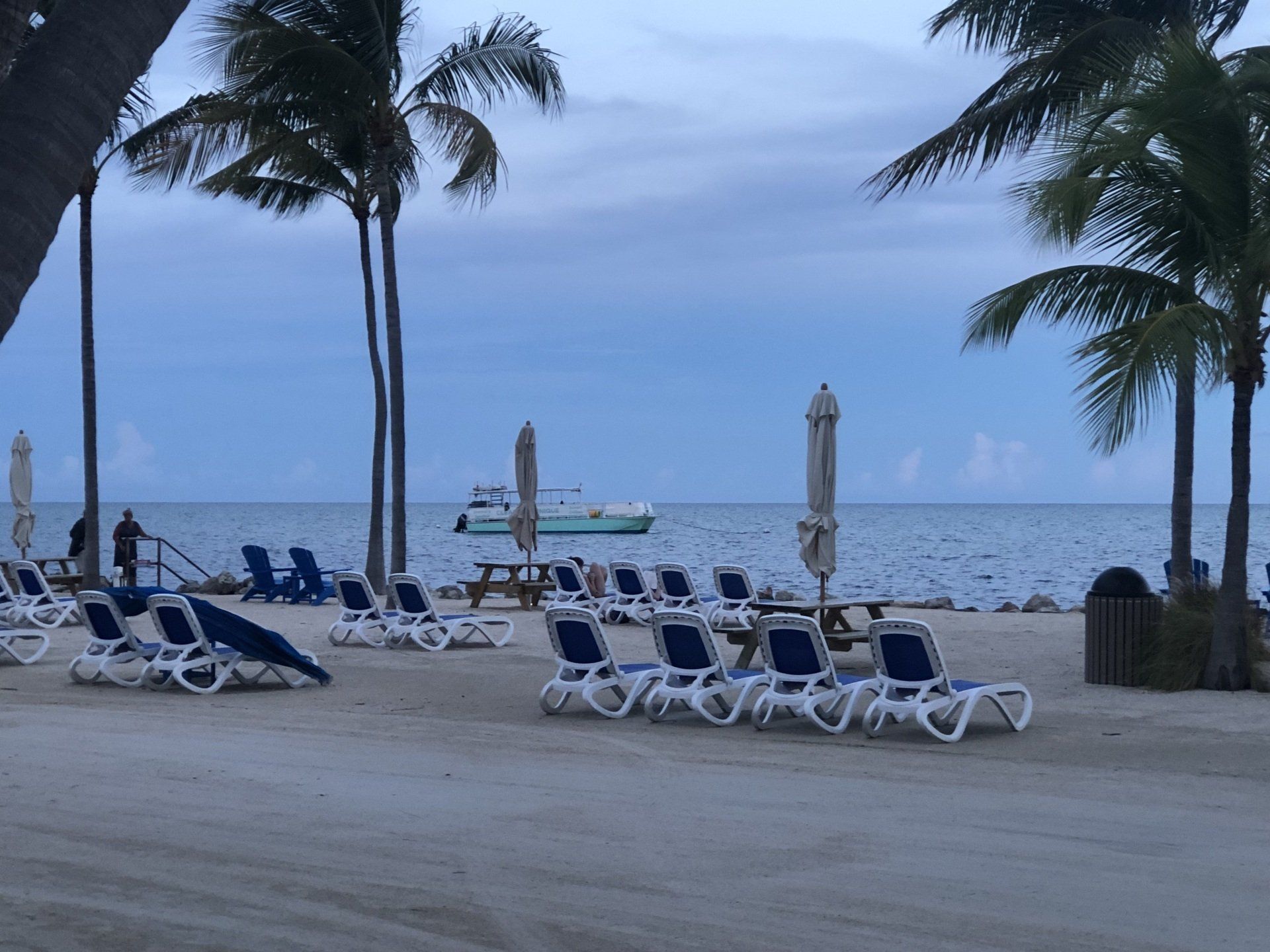 A beach with chairs and umbrellas and a boat in the background