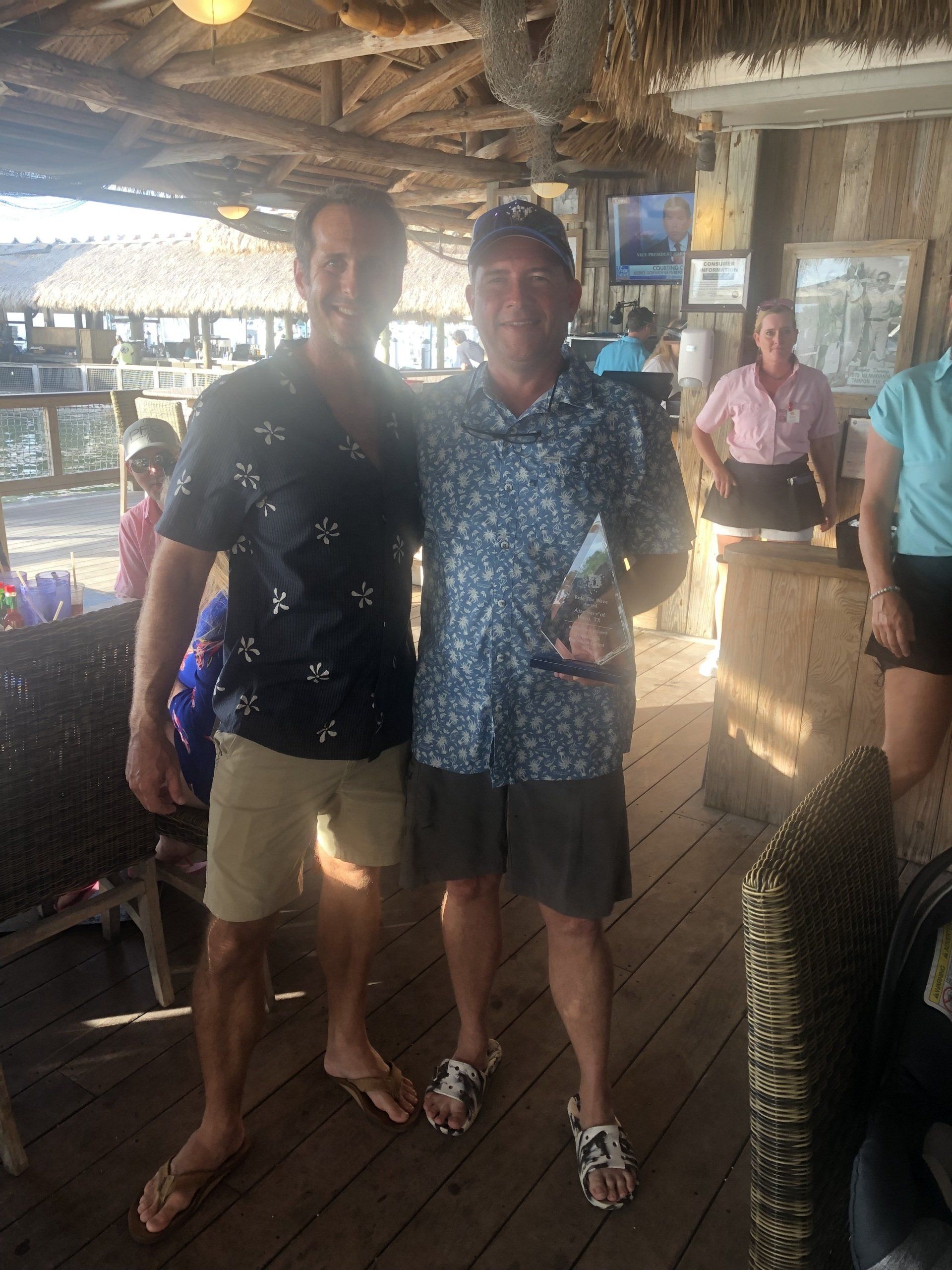 Two men are standing next to each other on a wooden deck.