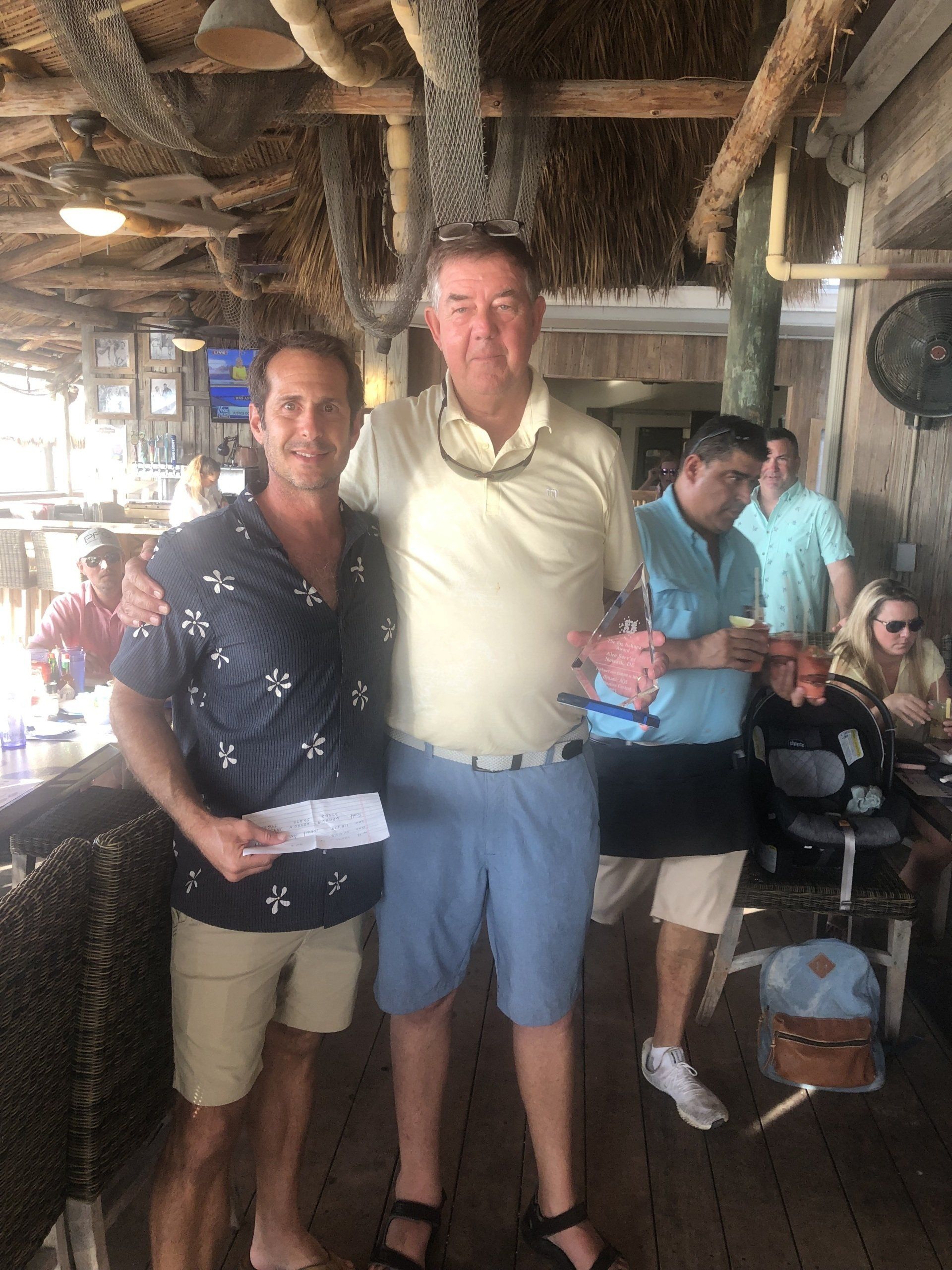 Two men are standing next to each other in a restaurant.