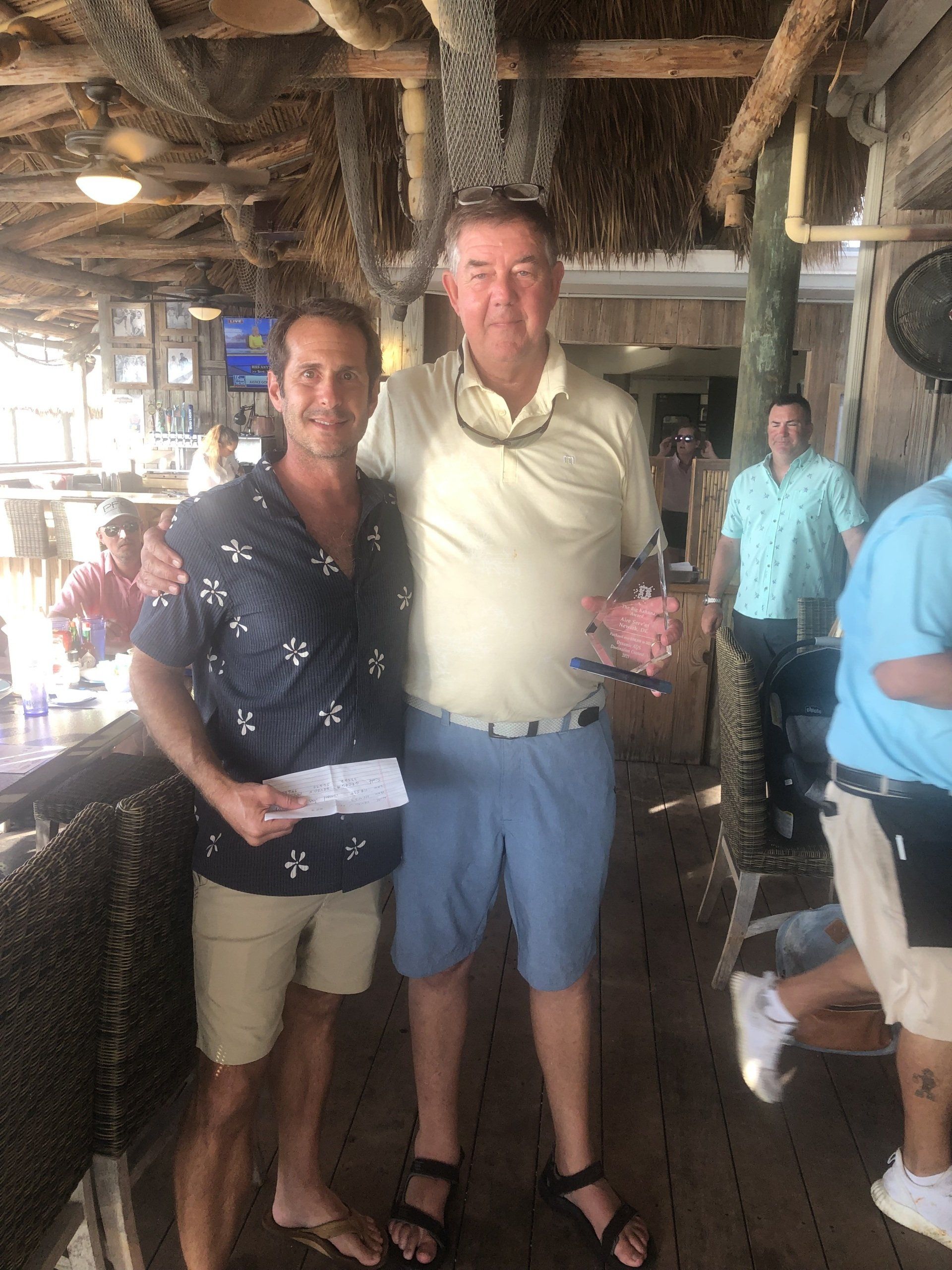 Two men are standing next to each other in a restaurant.
