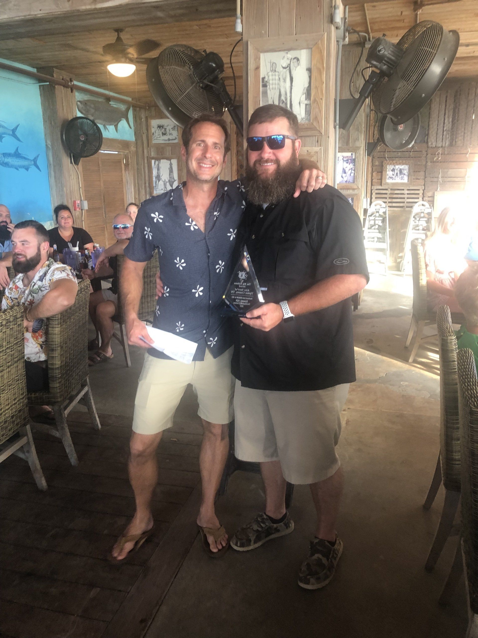 Two men are standing next to each other in a restaurant.