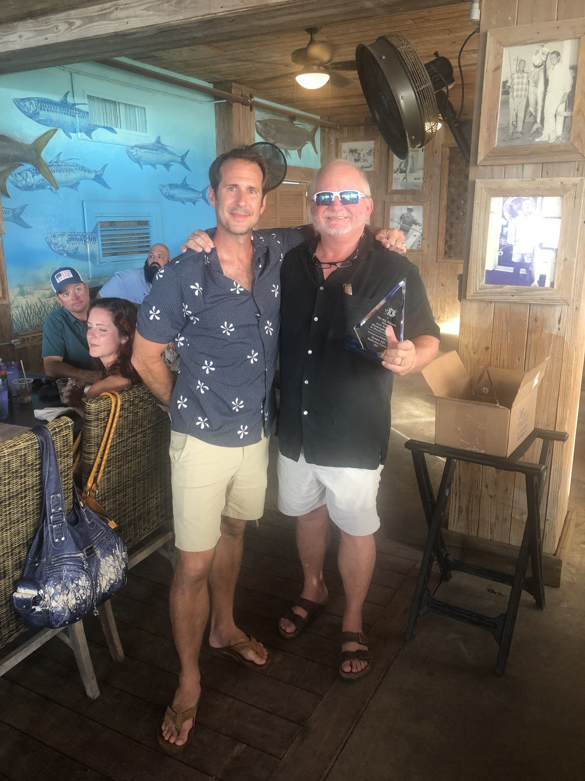 Two men are posing for a picture in a restaurant.