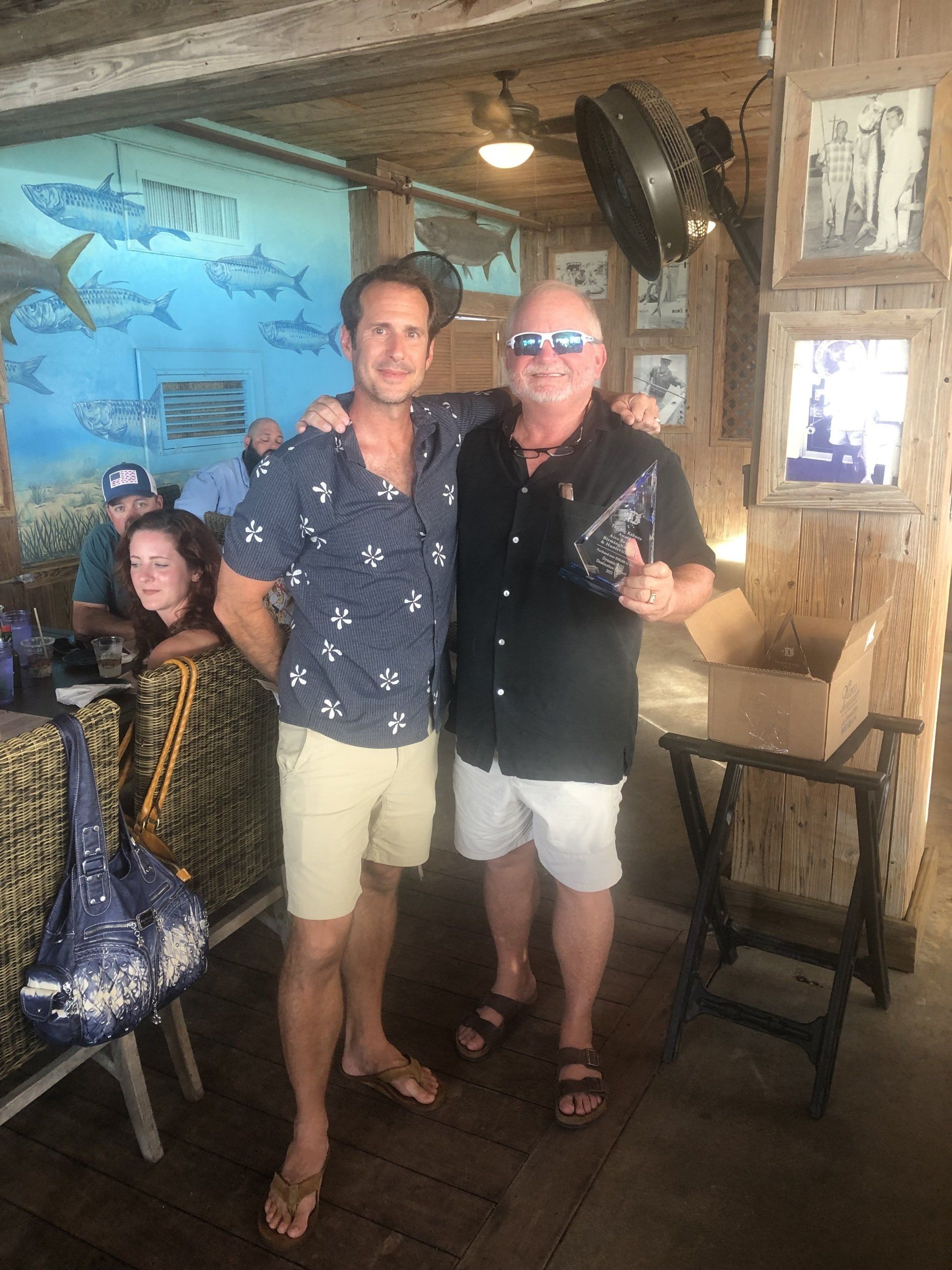 Two men are posing for a picture in a restaurant.