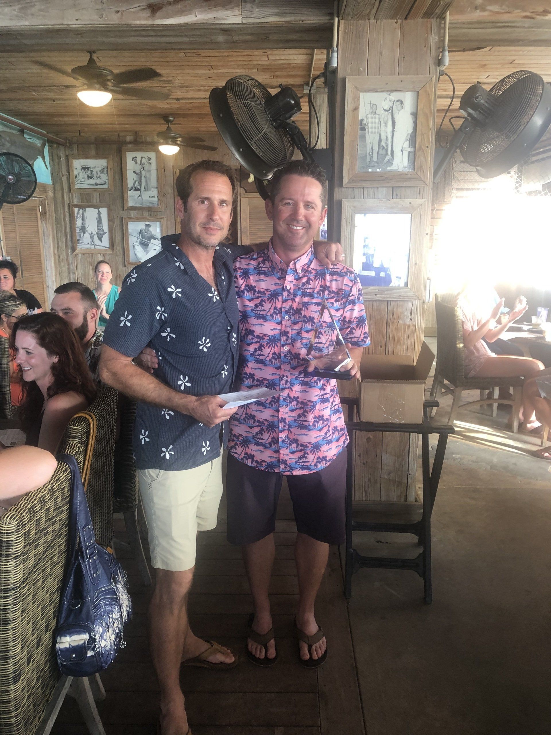 Two men are standing next to each other in a restaurant.
