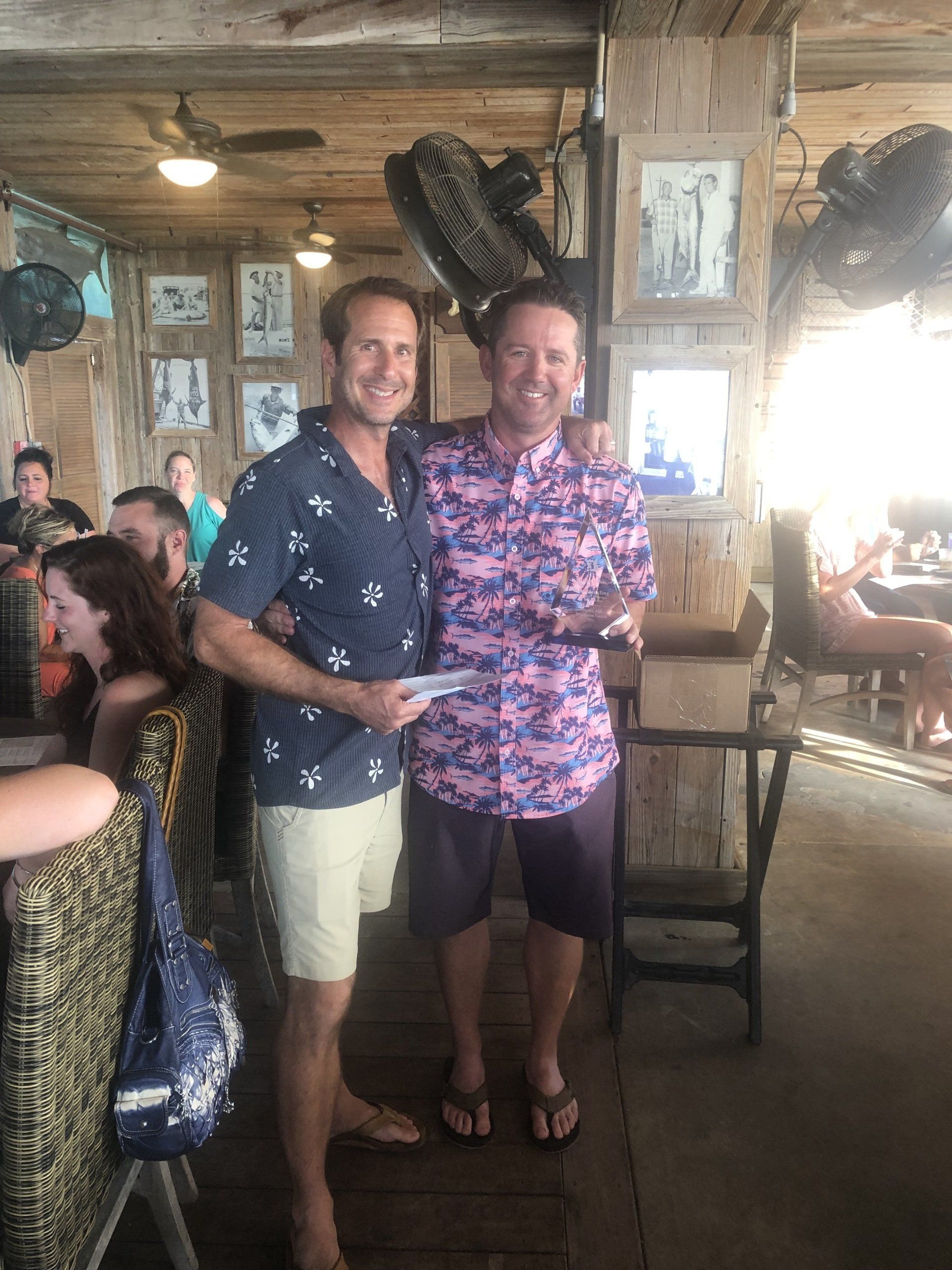 Two men are standing next to each other in a restaurant holding a check.